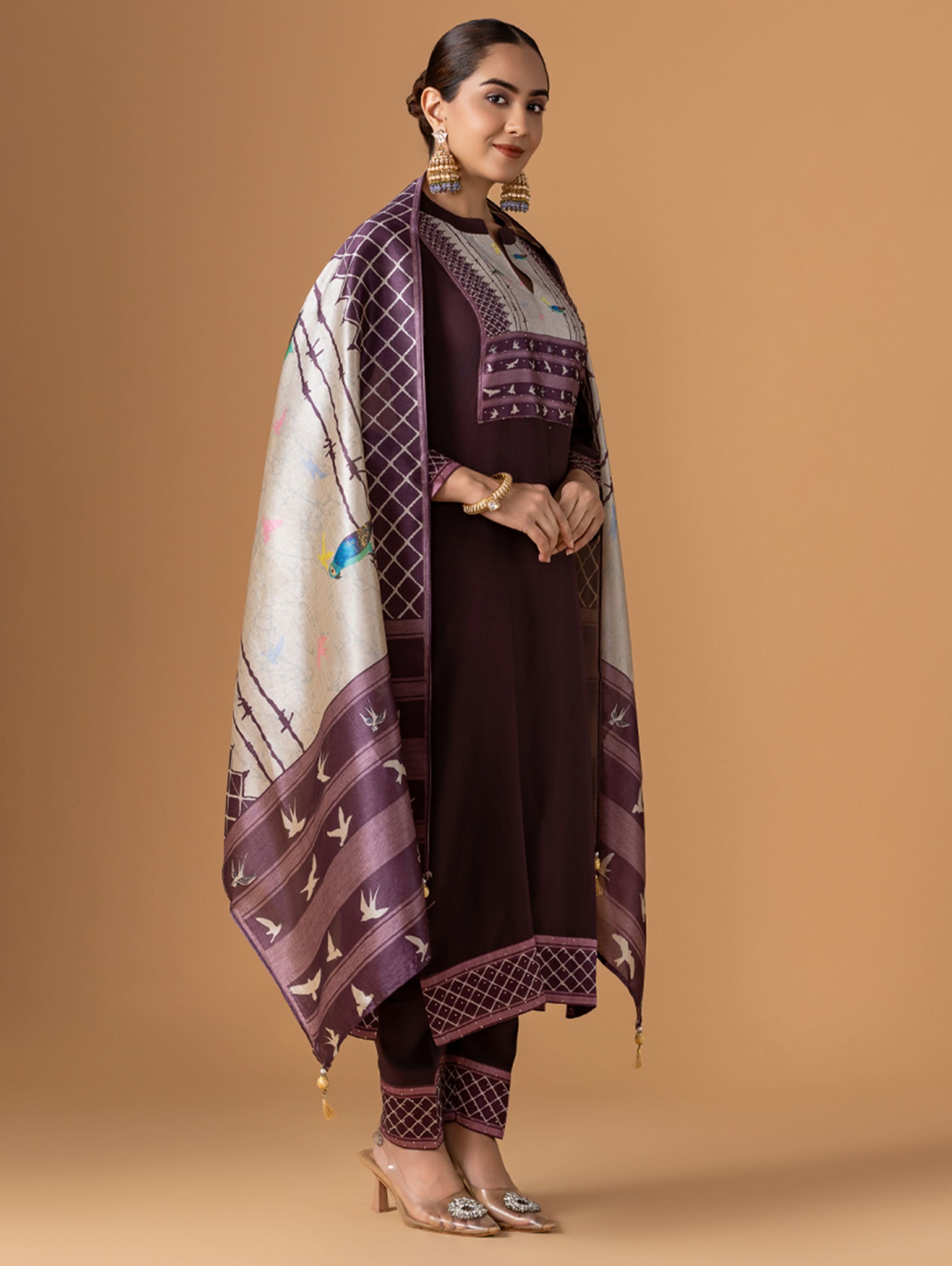 Woman wearing a traditional outfit with a patterned shawl on a beige background
