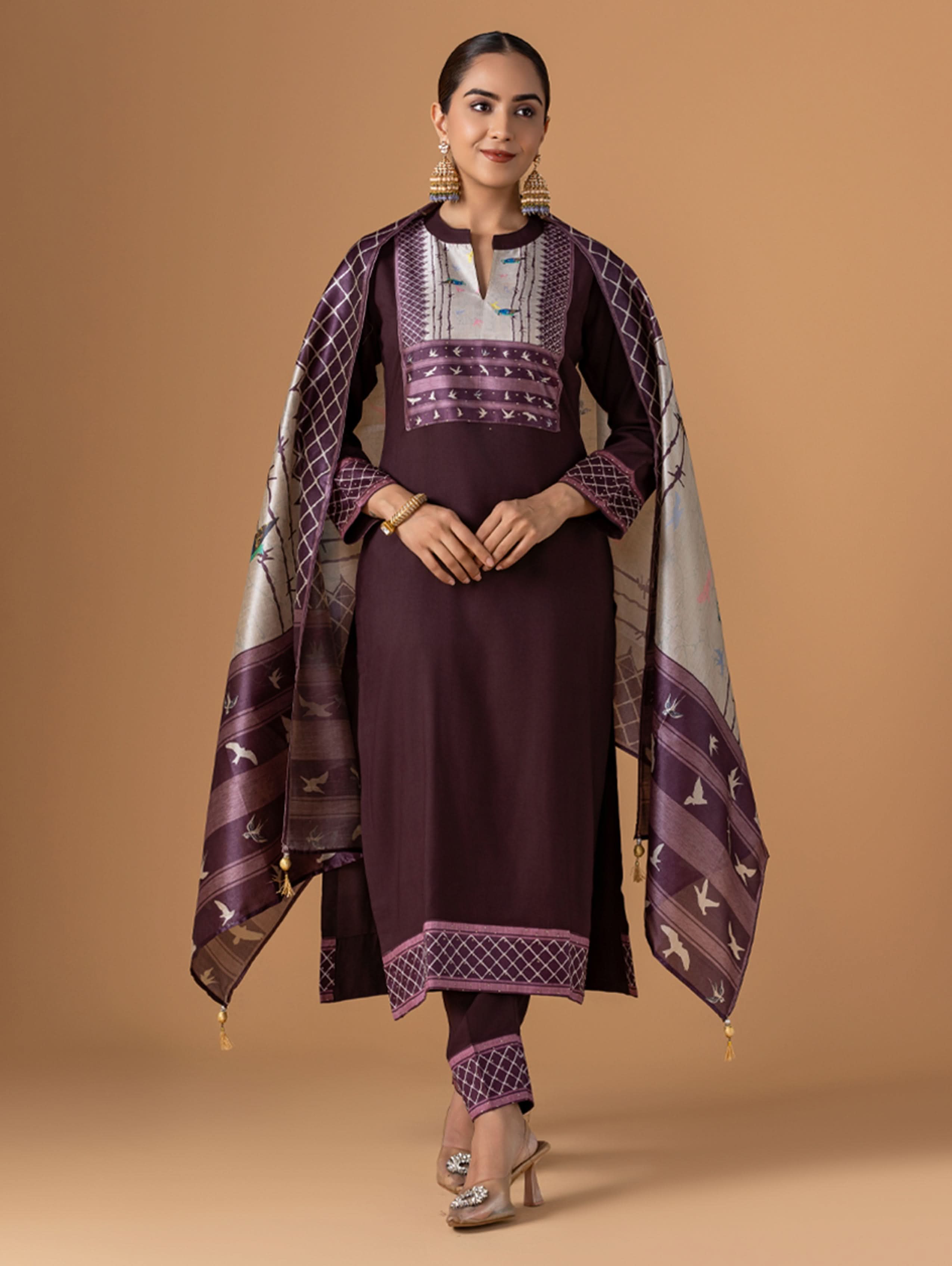Woman wearing a traditional outfit with a purple and white patterned shawl on a brown background