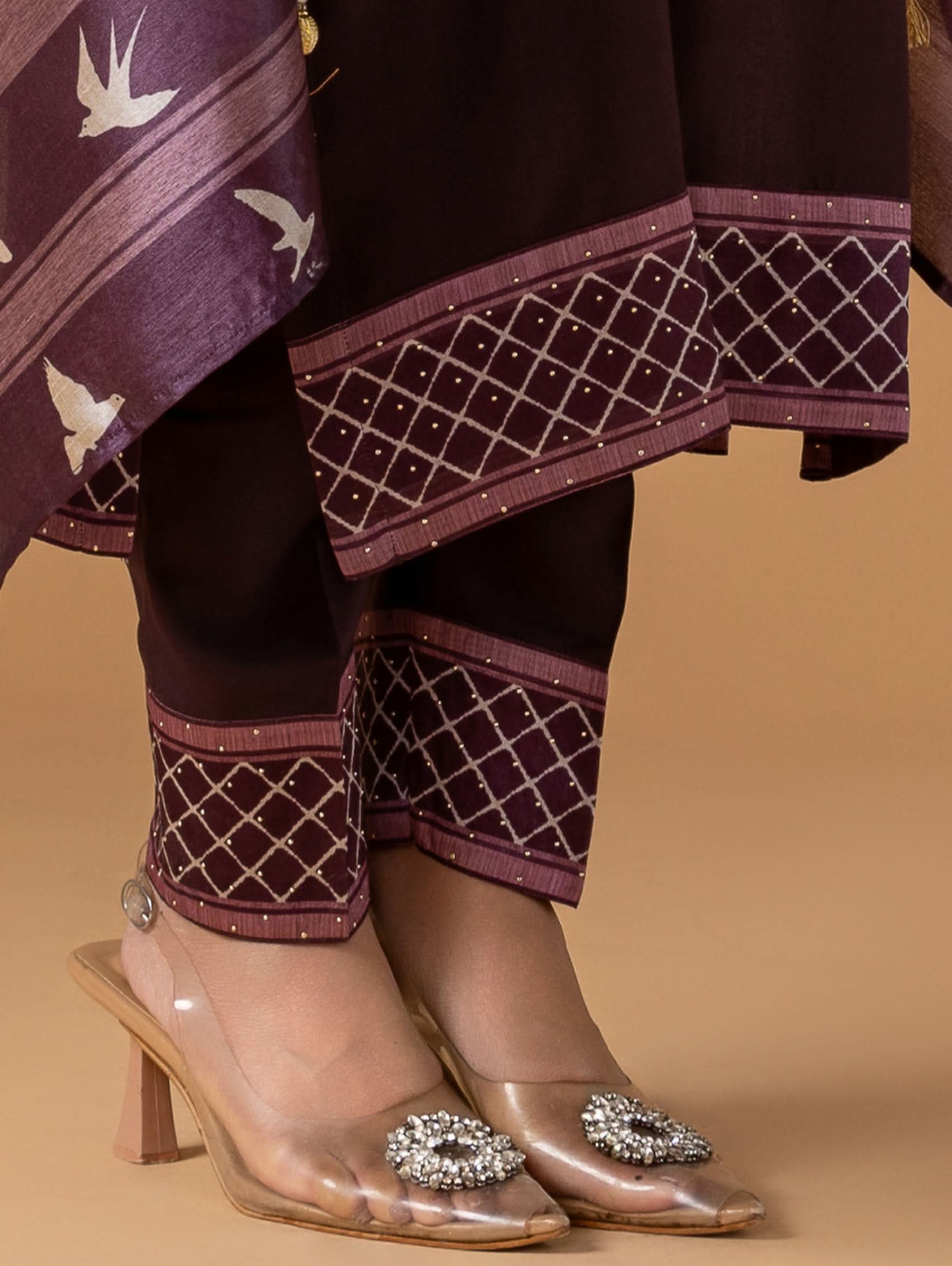 Traditional outfit with embroidered pants and transparent high-heeled shoes on a beige background