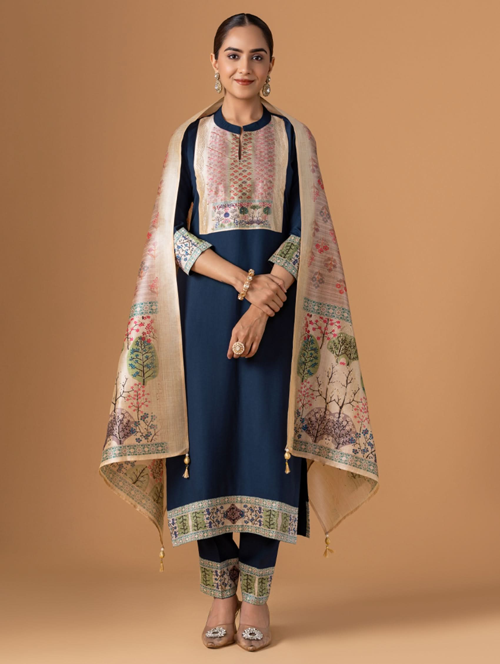 Woman wearing a traditional outfit with a floral dupatta against a beige background