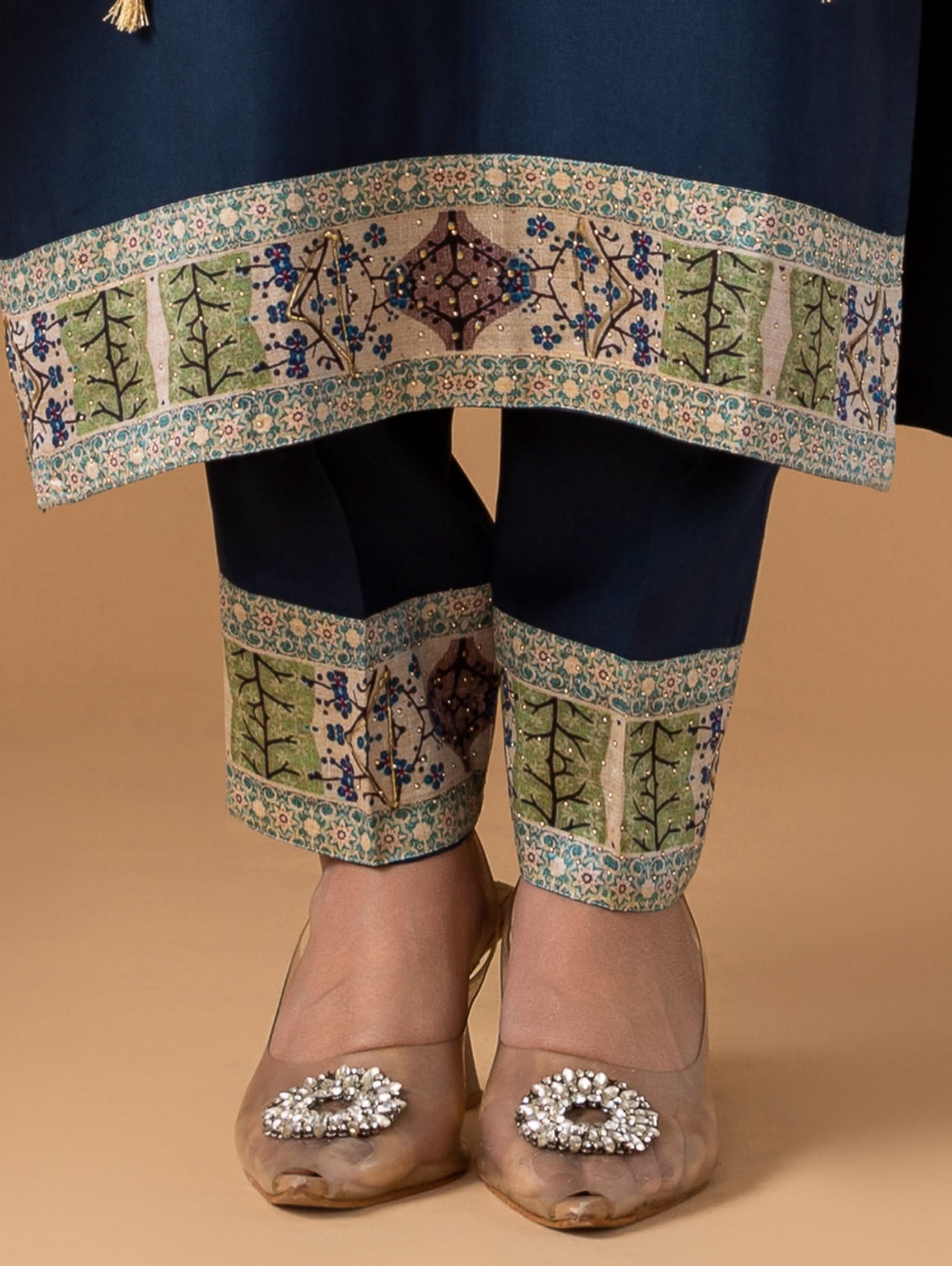 Traditional outfit with embroidered top and pants on a beige background