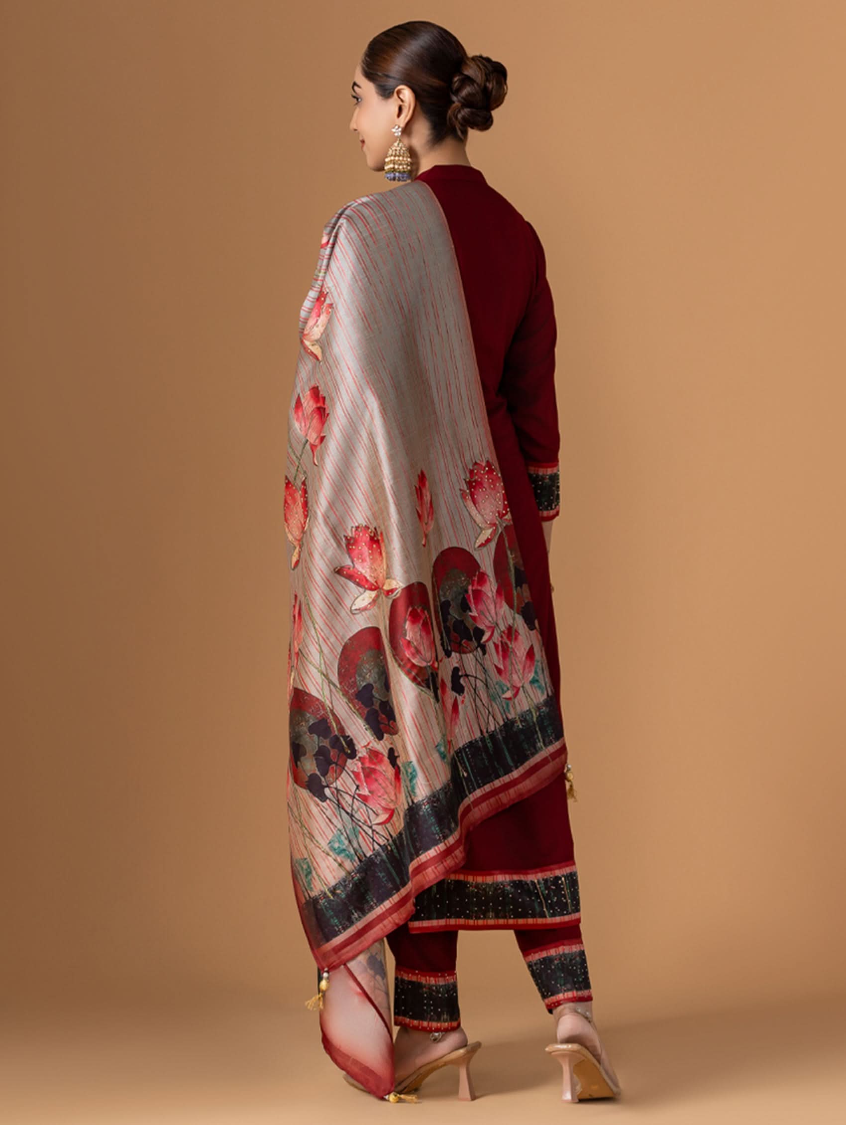Woman wearing a floral dupatta over a red outfit on a beige background