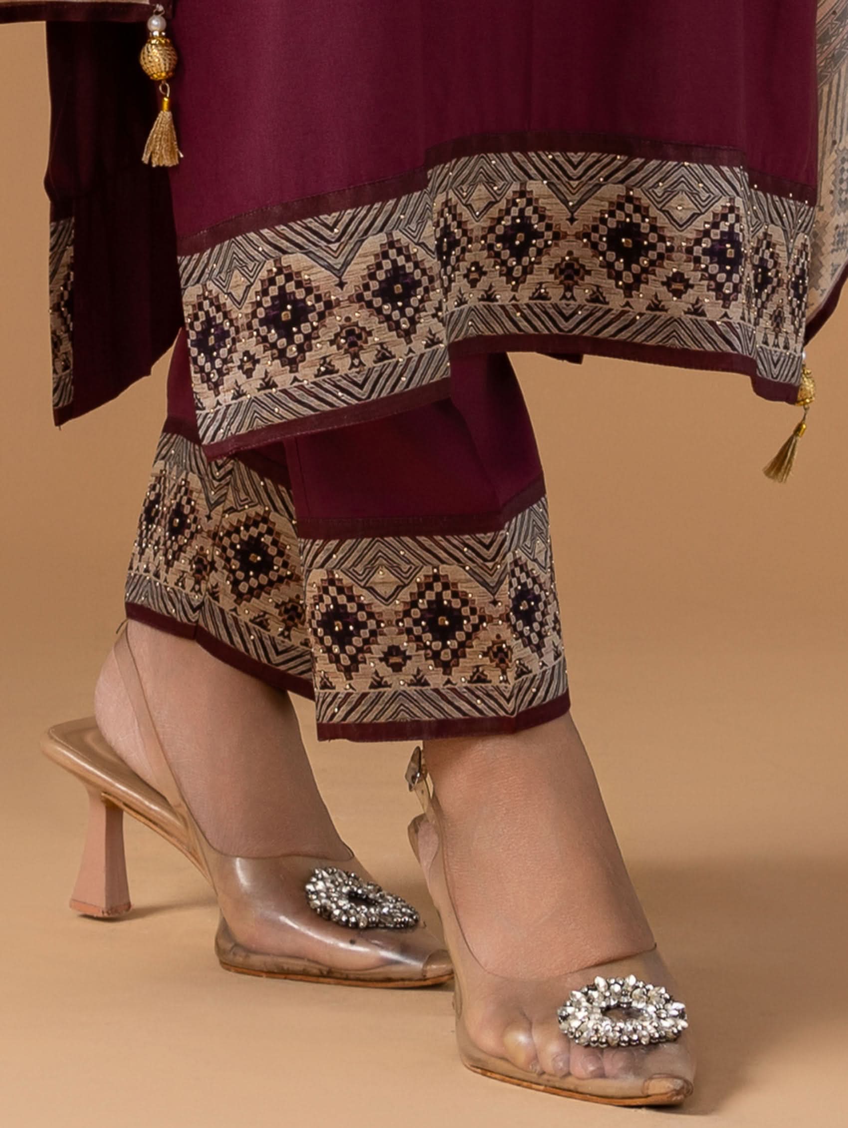 Traditional outfit with patterned fabric and transparent sandals on a beige background
