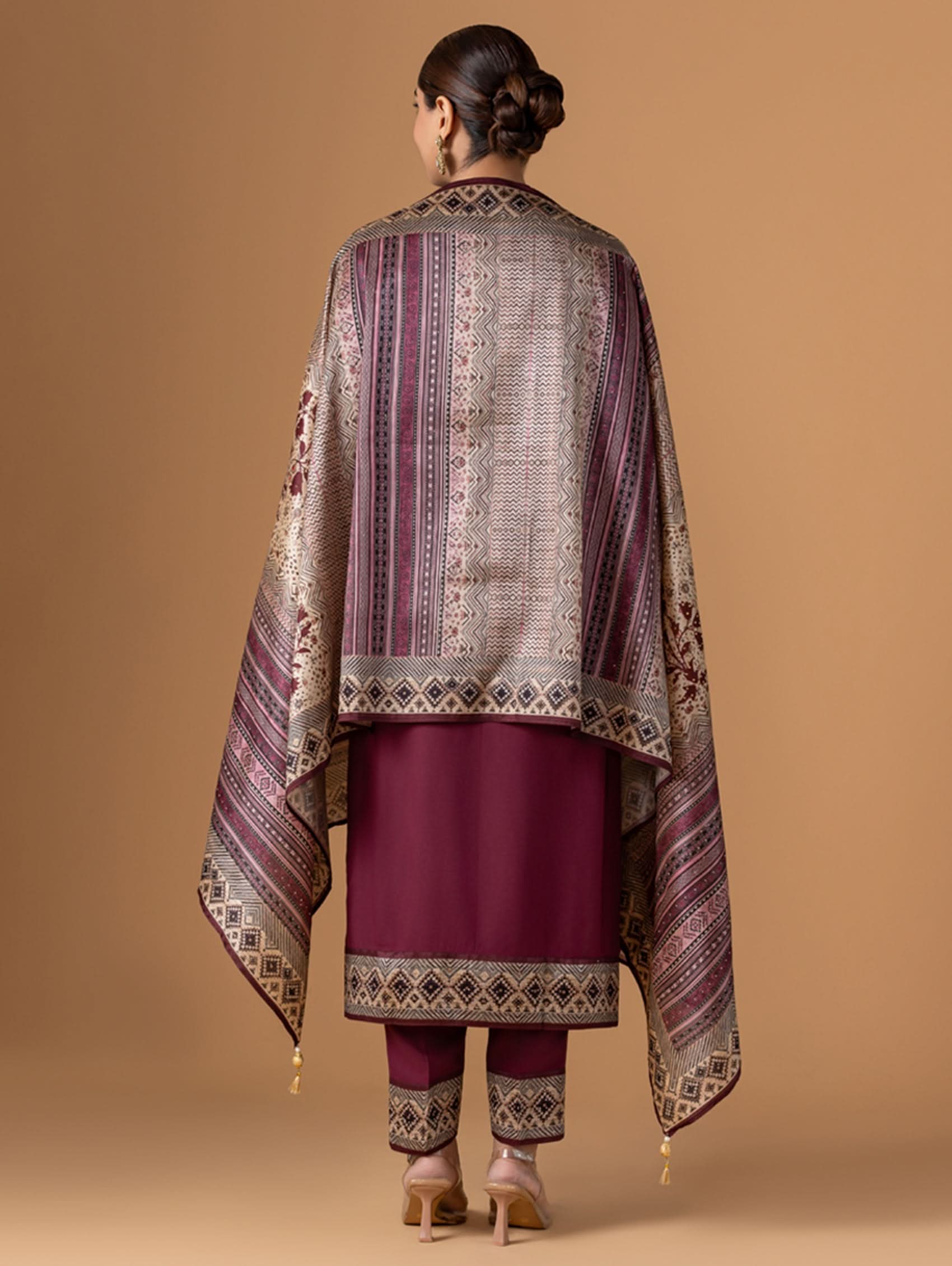 Woman wearing a traditional outfit with a patterned shawl on a beige background