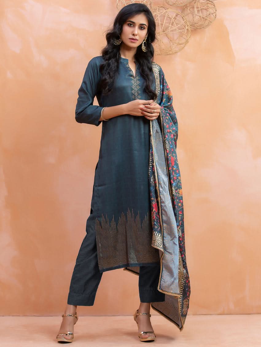 Woman wearing a dark blue traditional outfit with a patterned dupatta against a beige background