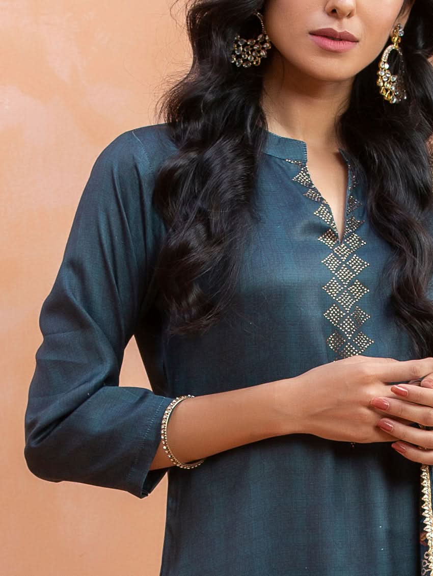 Woman wearing a dark blue kurta with gold embroidery against a beige background