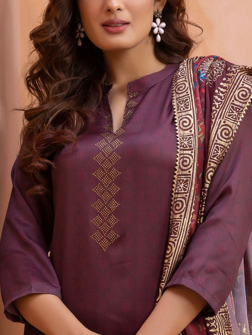 Woman wearing a purple embroidered top with a patterned shawl on a beige background