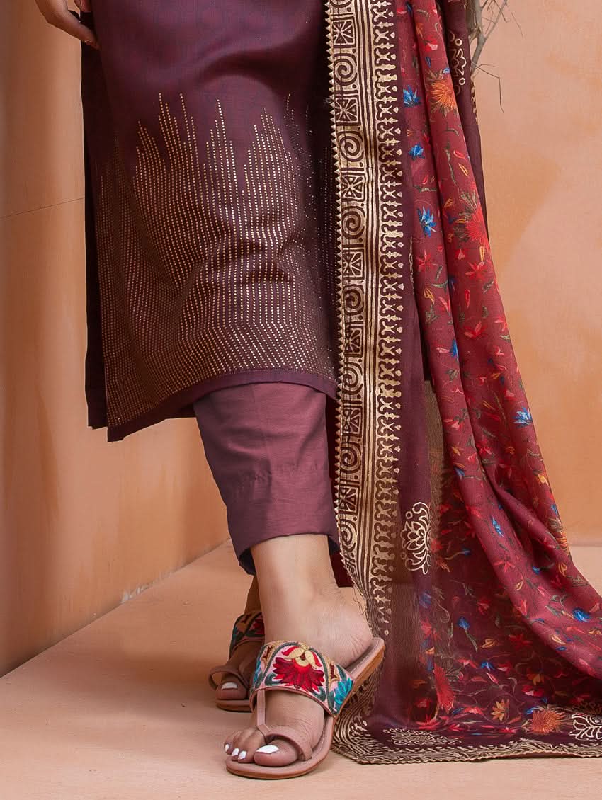 Person wearing a maroon outfit with a patterned scarf on a beige background