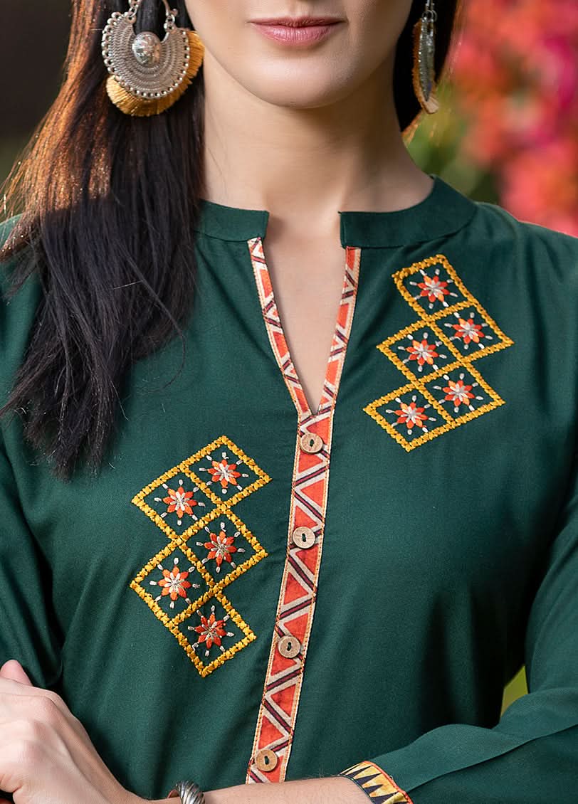 Green traditional outfit with intricate embroidery on a blurred natural background