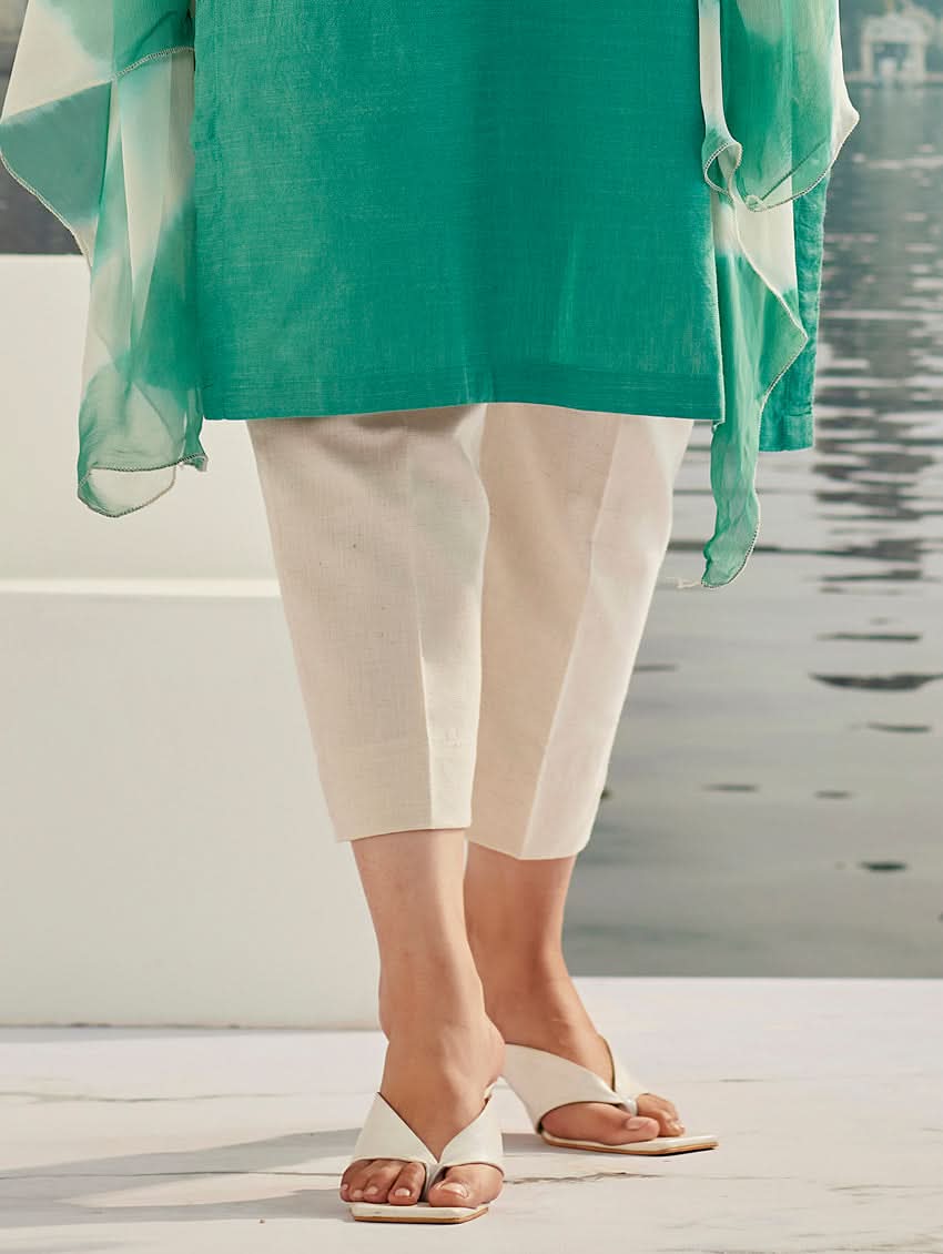 A woman wearing a solid-coloured cotton kurta with pants and a printed shiffon dupatta, standing against a backdrop of a traditional Indian palace.