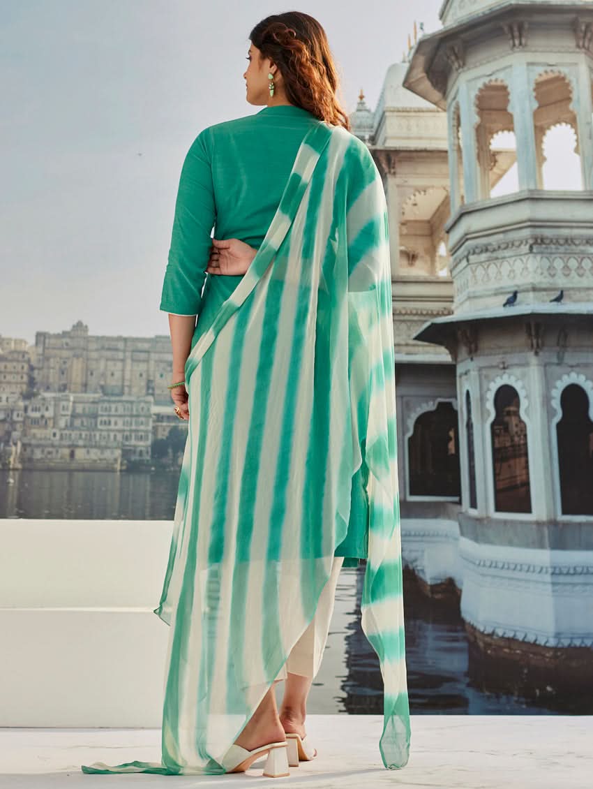 A woman wearing a solid-coloured cotton kurta with pants and a printed shiffon dupatta, standing against a backdrop of a traditional Indian palace.