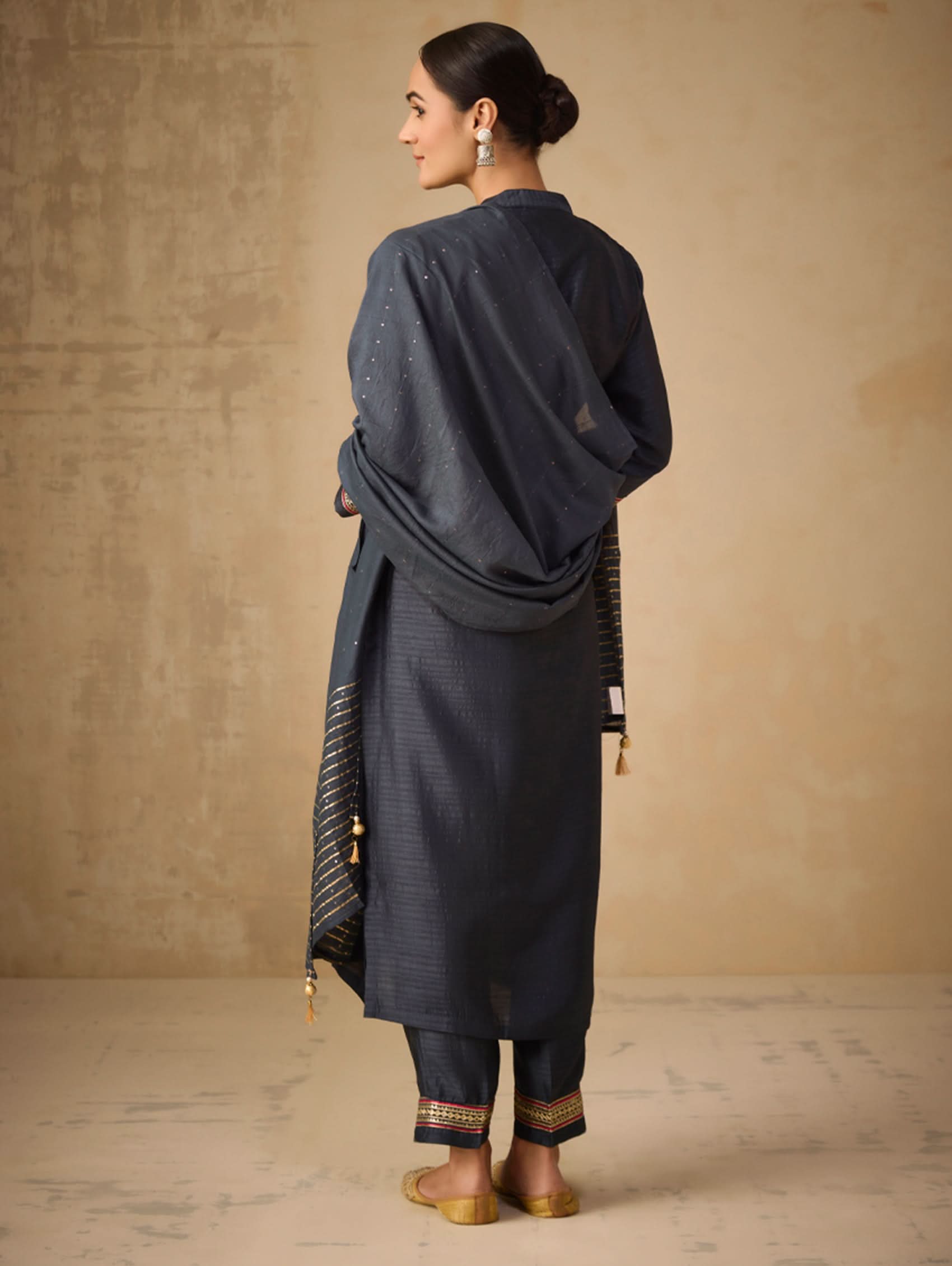 Woman wearing a dark blue traditional outfit against a beige background