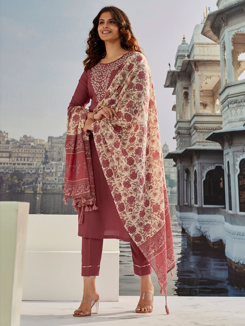 A woman wearing a solid-coloured rayon kurta with pants and a printed mul dupatta, standing against a backdrop of a traditional Indian palace.