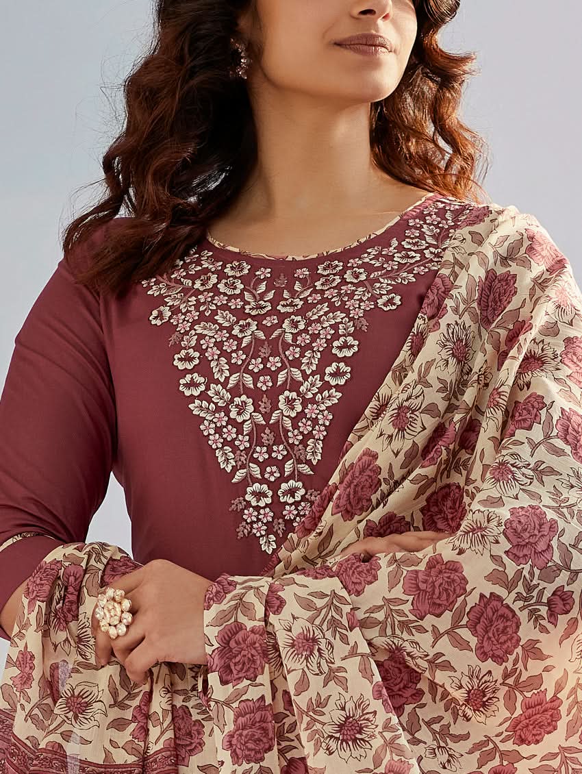 A woman wearing a solid-coloured rayon kurta with pants and a printed mul dupatta, standing against a backdrop of a traditional Indian palace.