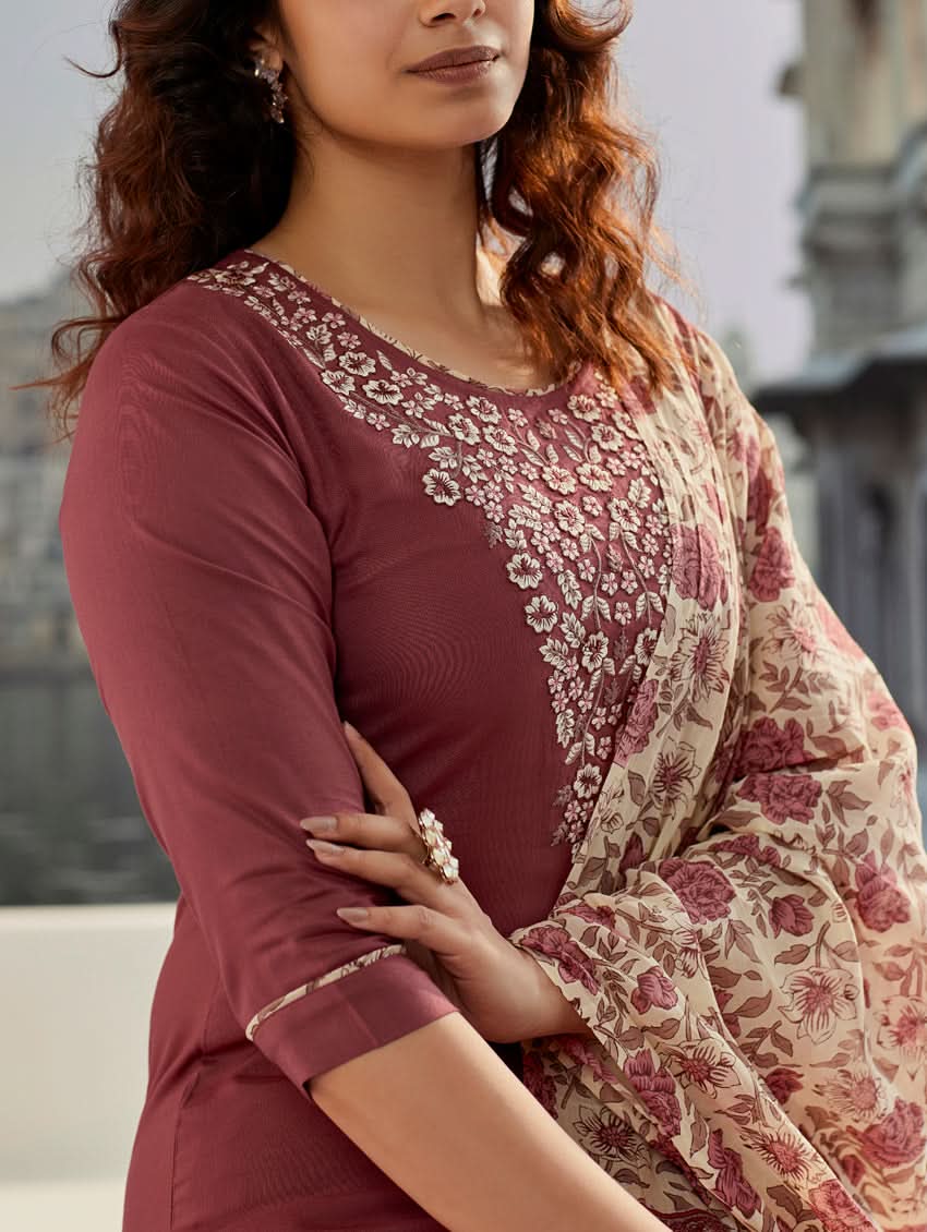 A woman wearing a solid-coloured rayon kurta with pants and a printed mul dupatta, standing against a backdrop of a traditional Indian palace.