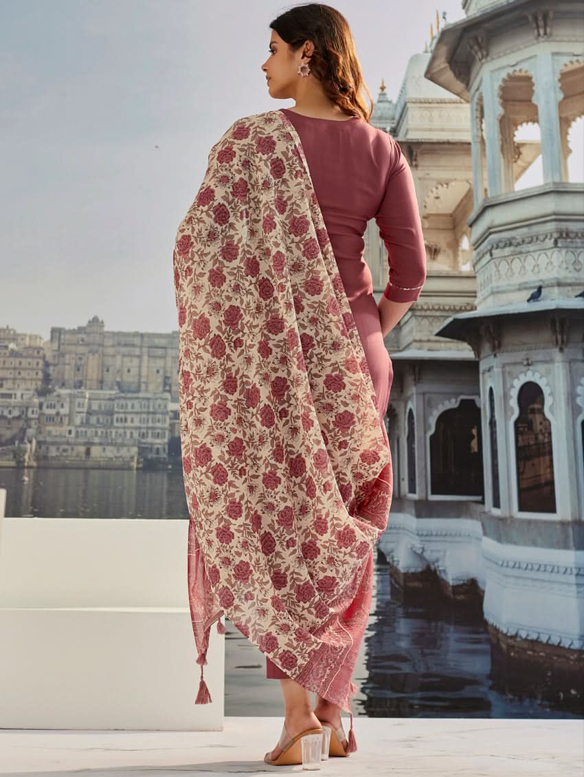 A woman wearing a solid-coloured rayon kurta with pants and a printed mul dupatta, standing against a backdrop of a traditional Indian palace.