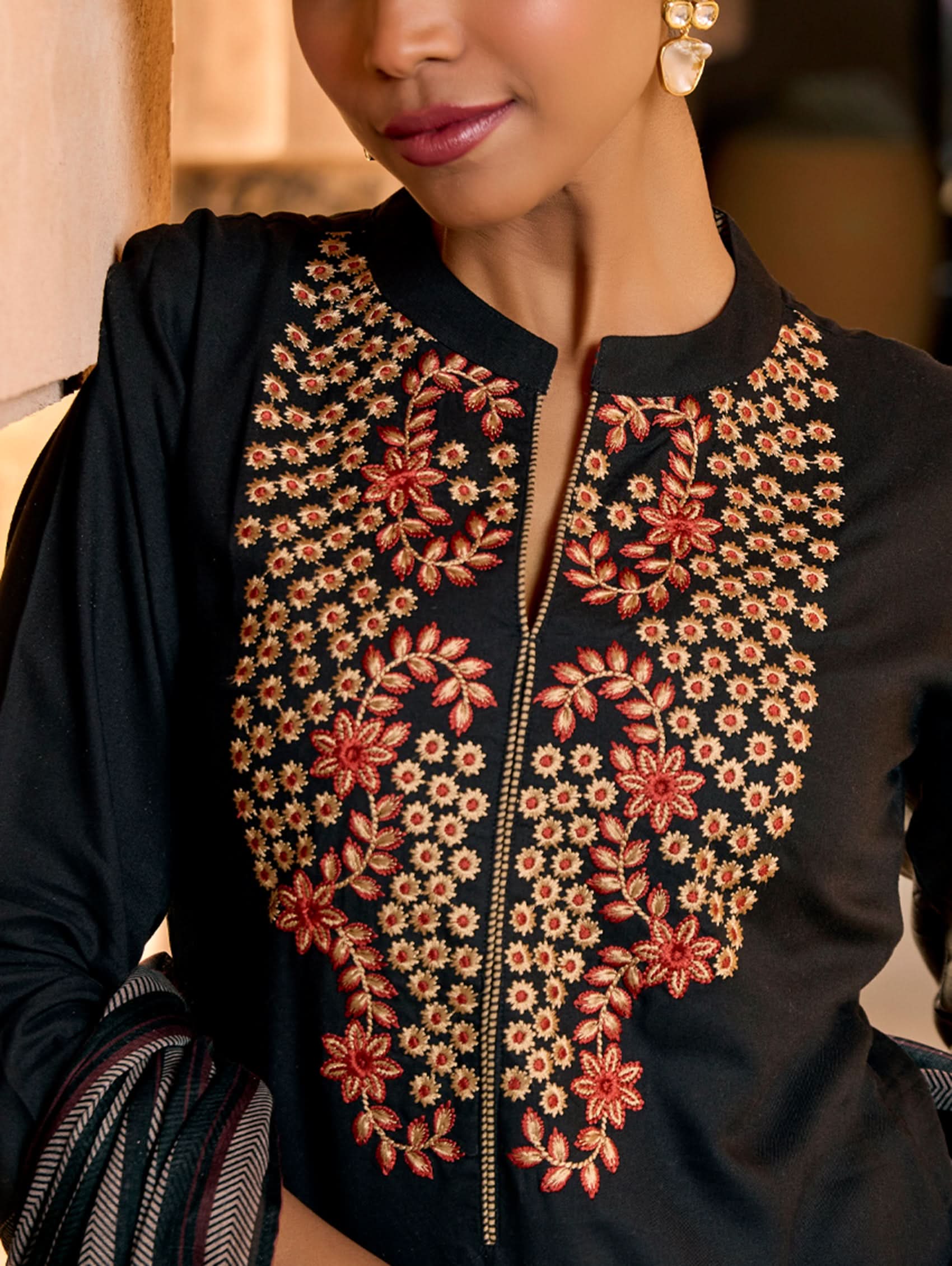 A woman wearing a black viscose rayon suit set with embroidery, consisting of a kurta and pants, and a printed dupatta.