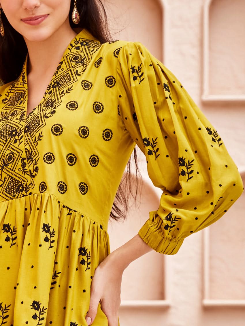 A woman standing on a balcony wearing an embroidered Yellow kurta set with V-neckline and three-quarter sleeves, paired with black pants with a partially elasticated waistband and pockets on either side.