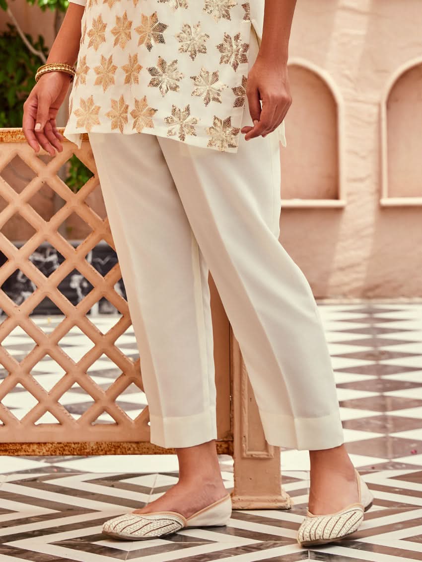 A woman standing beautiful studio wearing a white embellished viscose flex co-ord set with short kurta and pants,