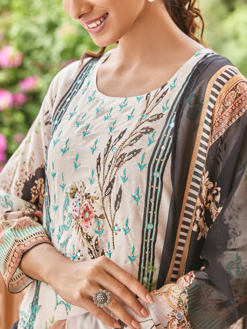 A woman wearing a traditional digital printed silk suit set with a dupatta, featuring a round neckline, three-fourth sleeves, and side slits. The set has a vibrant floral design.