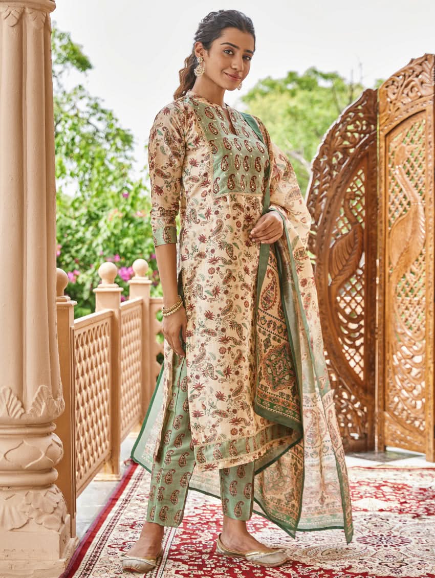 A woman standing in an ornate room wearing a traditional digital printed silk suit set with a dupatta, featuring floral and geometric patterns.