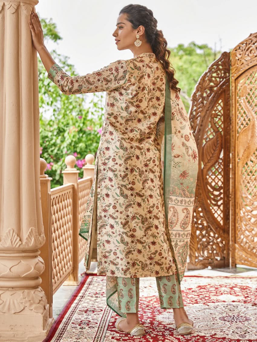 A woman standing in an ornate room wearing a traditional digital printed silk suit set with a dupatta, featuring floral and geometric patterns.
