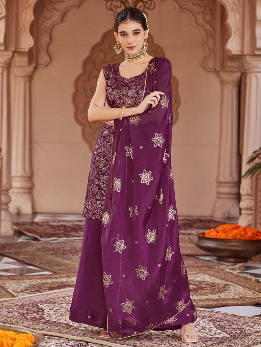A woman wearing a traditional purple Georgette suit set with embroidered sequins, consisting of a kurta with round neckline and sleeveless design, and a sharara with an elasticated waistband. The set is complemented by a dupatta.