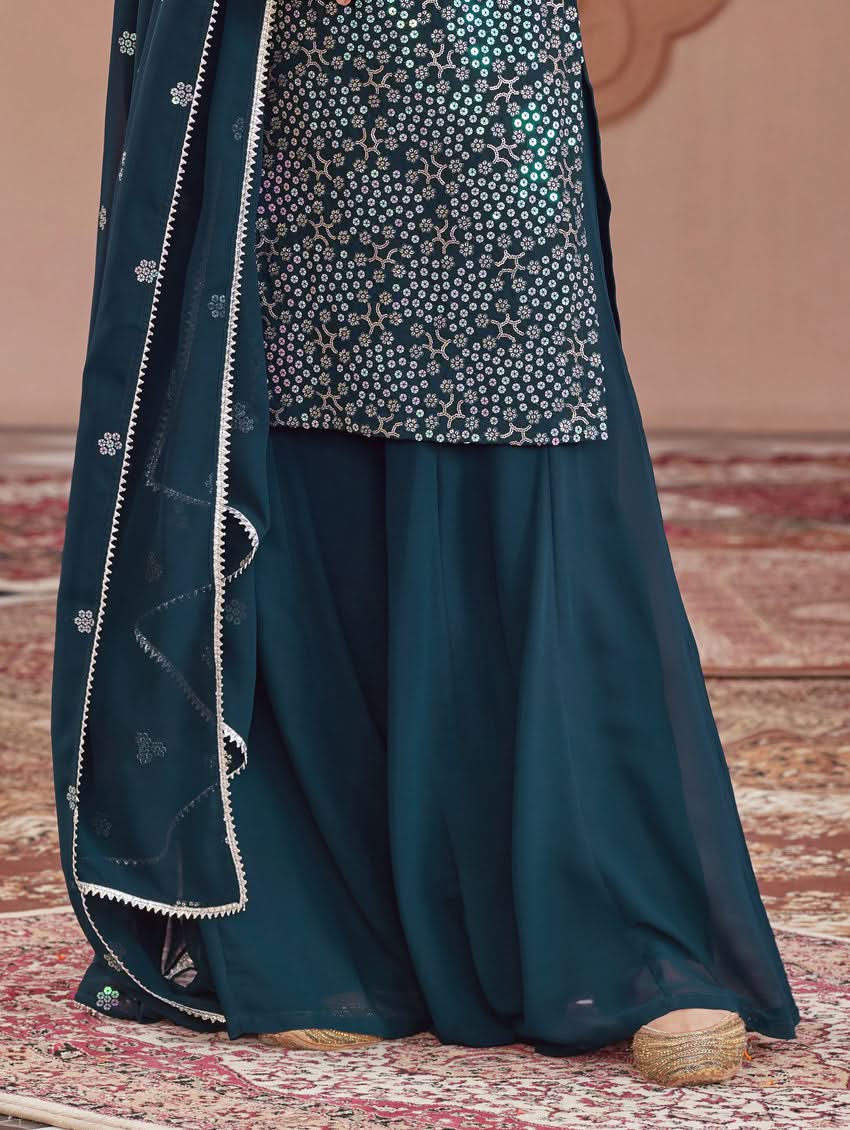 Embroidered dark teal tunic hem over flared sharara pants and bordered dupatta