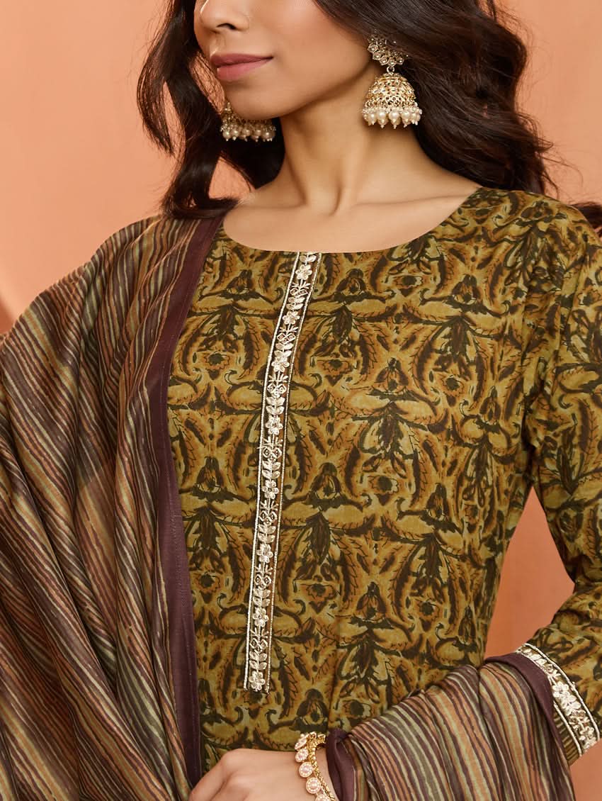 A woman wearing a traditional printed cotton suit set with a dupatta, featuring a boat neckline and embroidery details.