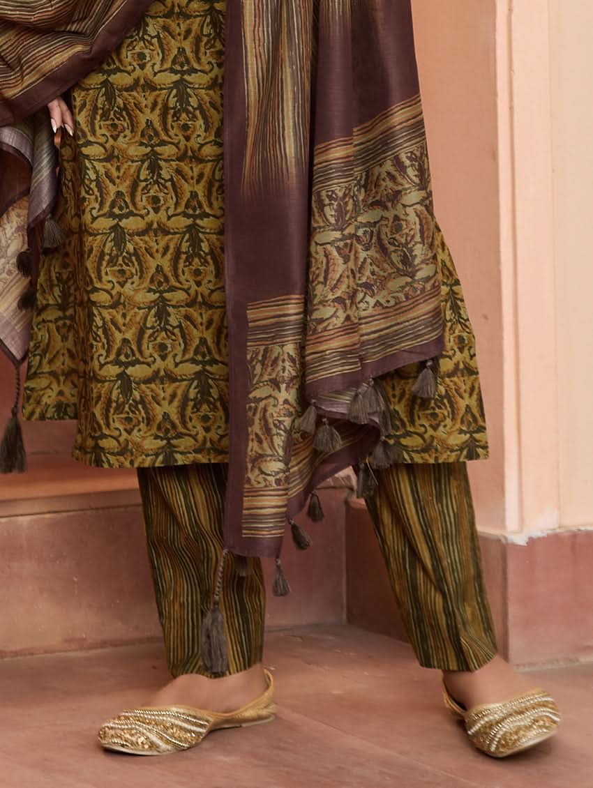 A woman wearing a traditional printed cotton suit set with a dupatta, featuring a boat neckline and embroidery details.