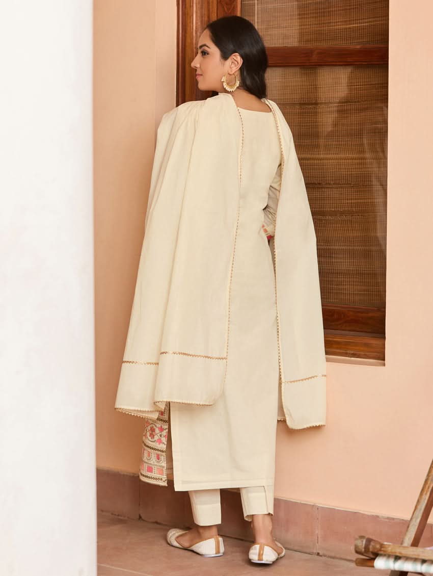 A woman wearing a traditional embroidered cotton suit set with a dupatta, featuring a round neckline and sequin-embroidered details.
