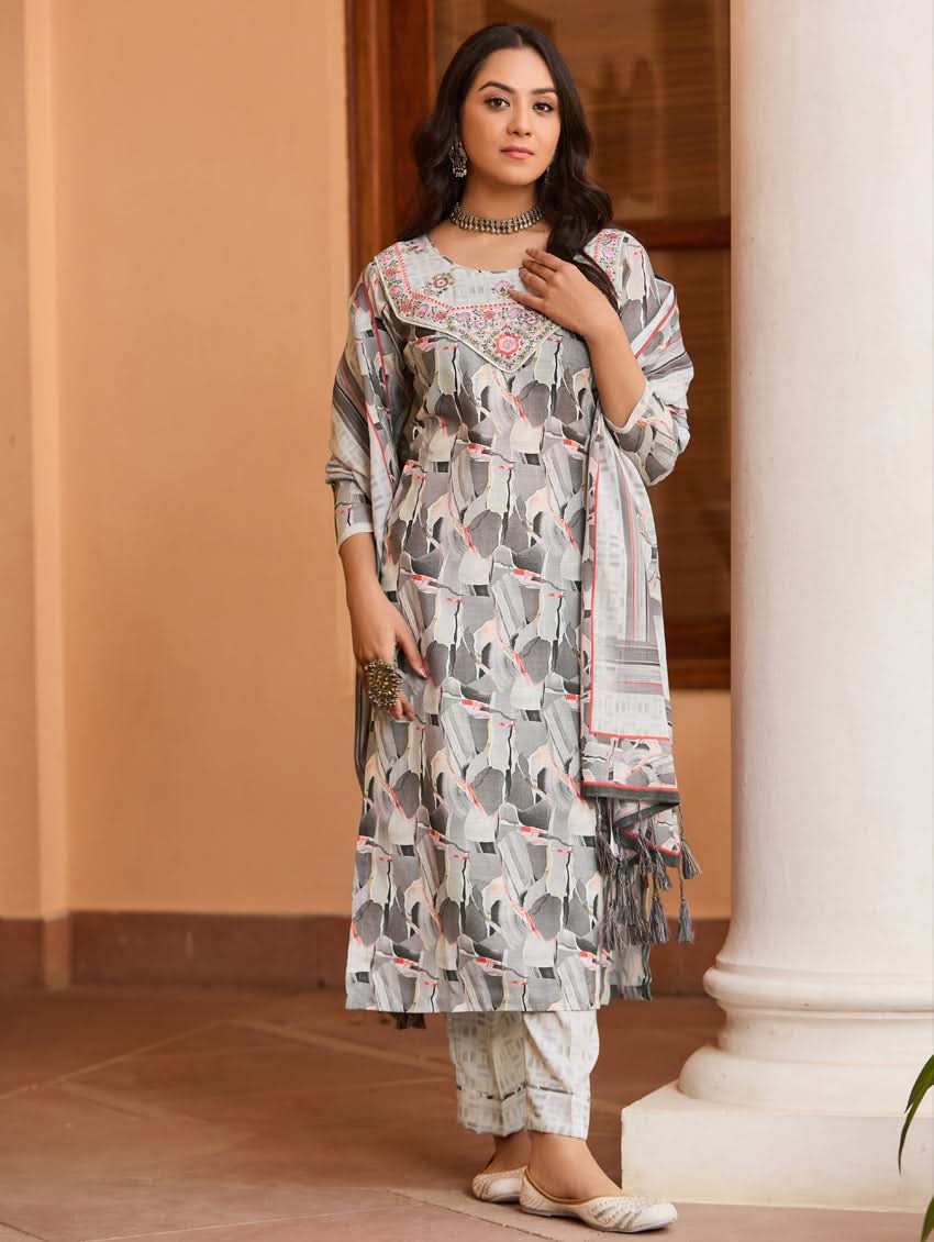 A woman wearing a digitally printed cotton linen suit set with a kurta, pants, and a dupatta. The suit set has a geometric pattern in muted colors.