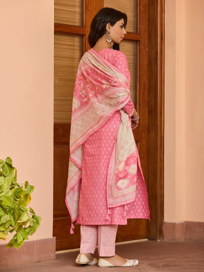 A woman wearing a pink kurta with three-fourth sleeves and side slits, paired with straight pants and a matching dupatta with floral print and tassels.