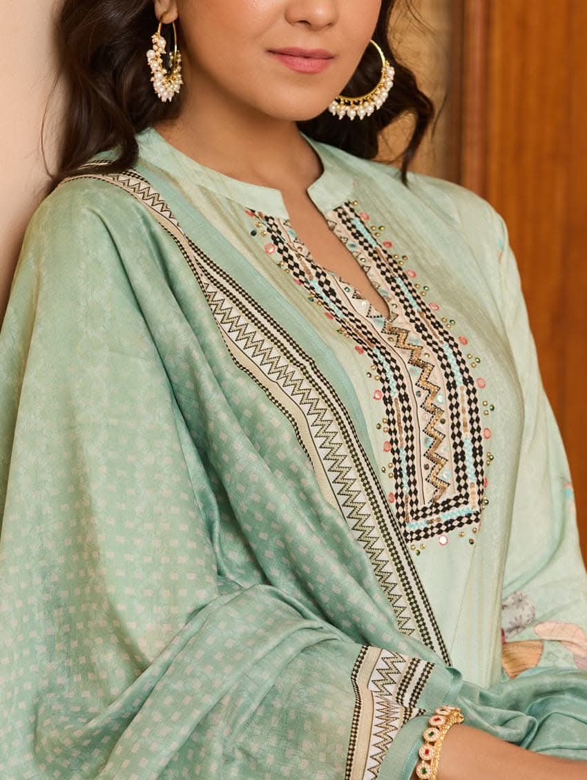 A woman wearing a green viscose rayon suit set with digitally printed patterns, consisting of a kurta with pants and a dupatta.