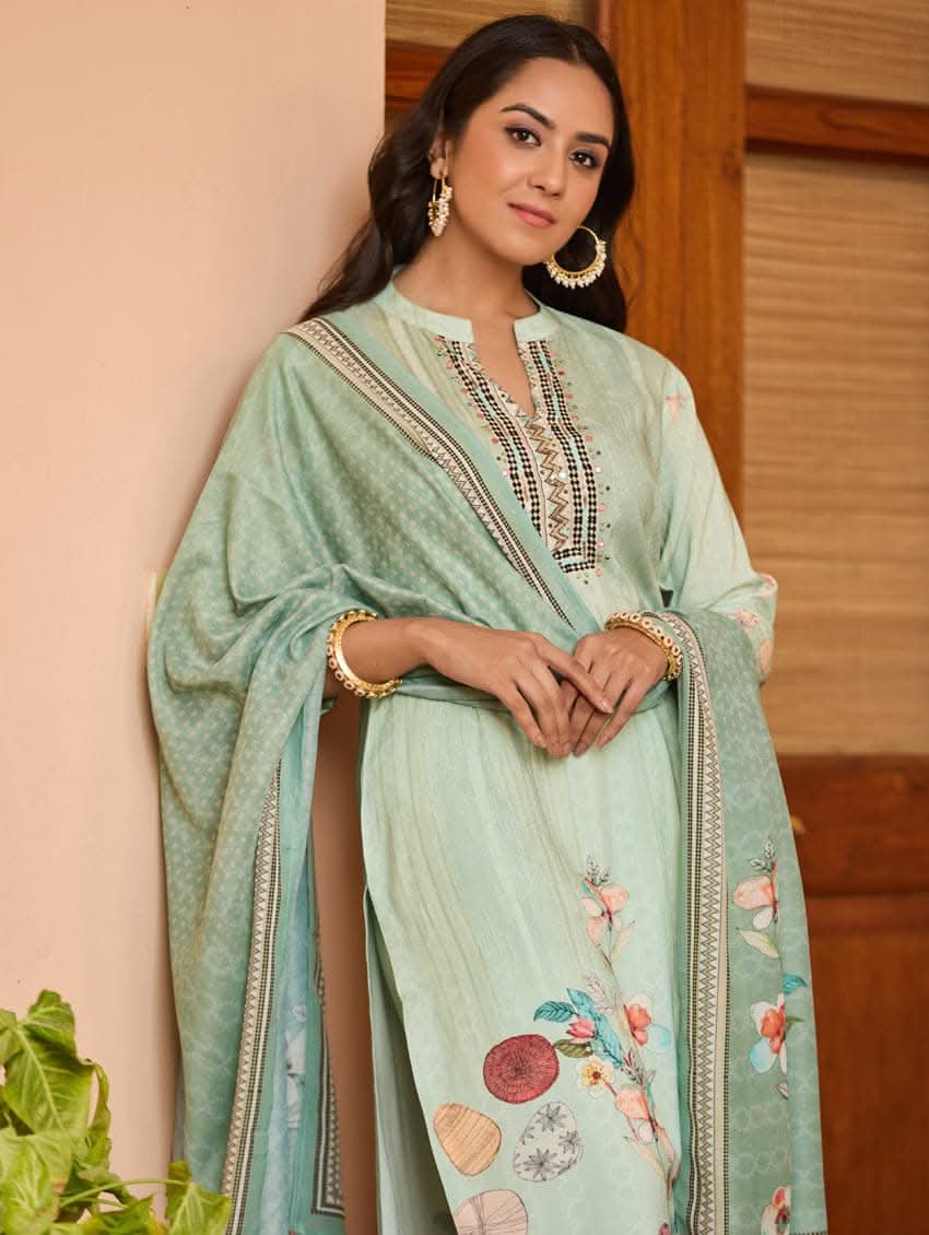 A woman wearing a green viscose rayon suit set with digitally printed patterns, consisting of a kurta with pants and a dupatta.