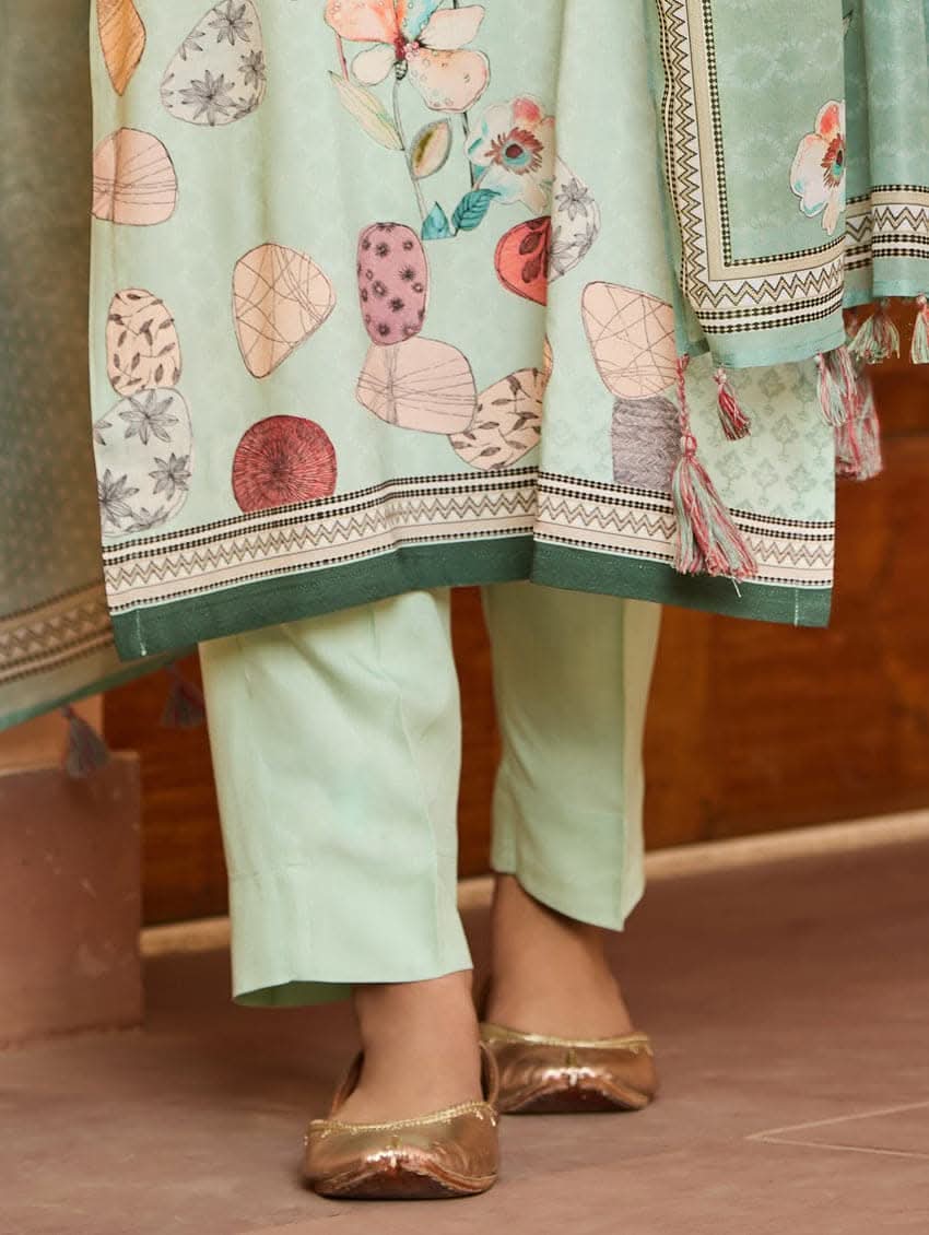 A woman wearing a green viscose rayon suit set with digitally printed patterns, consisting of a kurta with pants and a dupatta.