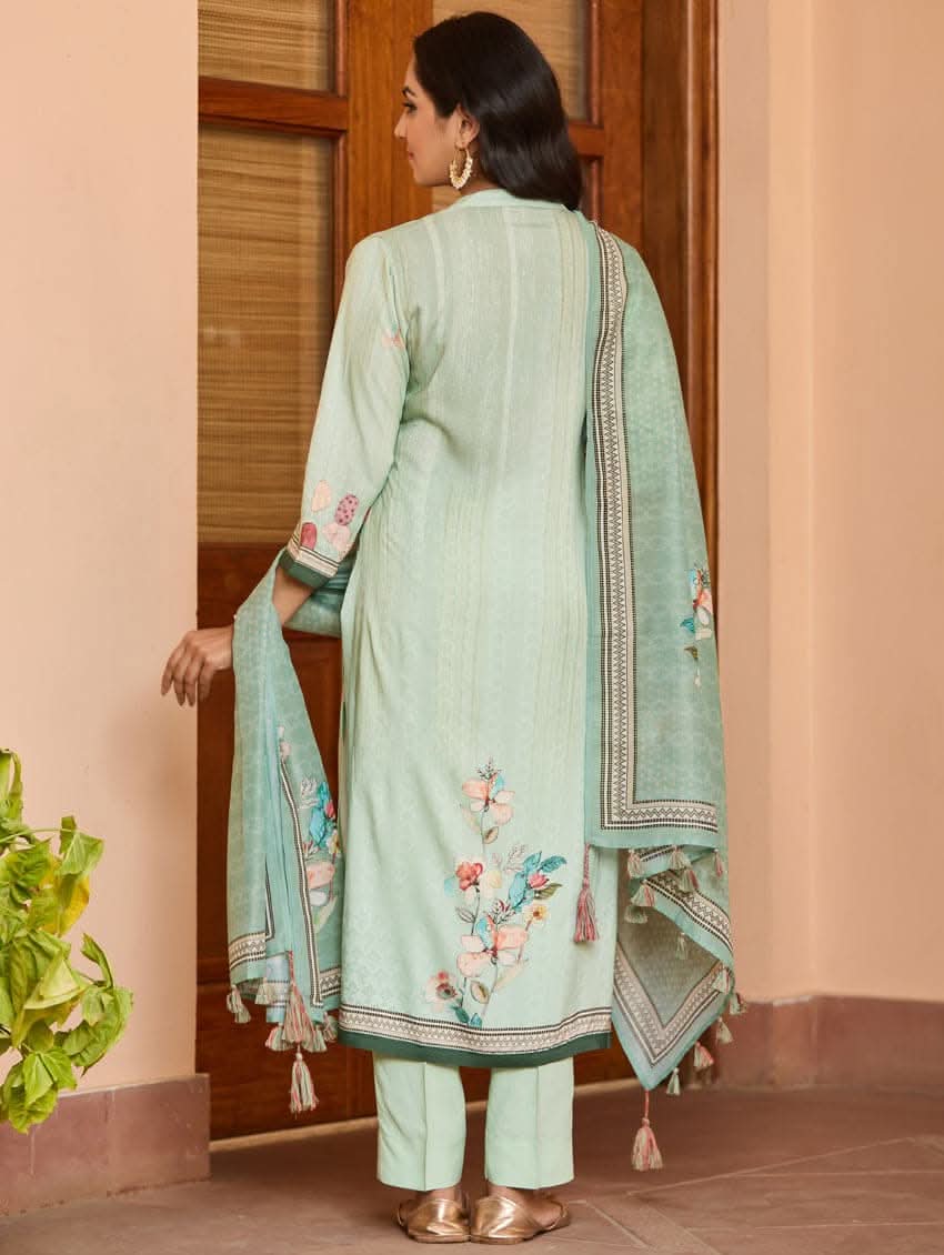 A woman wearing a green viscose rayon suit set with digitally printed patterns, consisting of a kurta with pants and a dupatta.