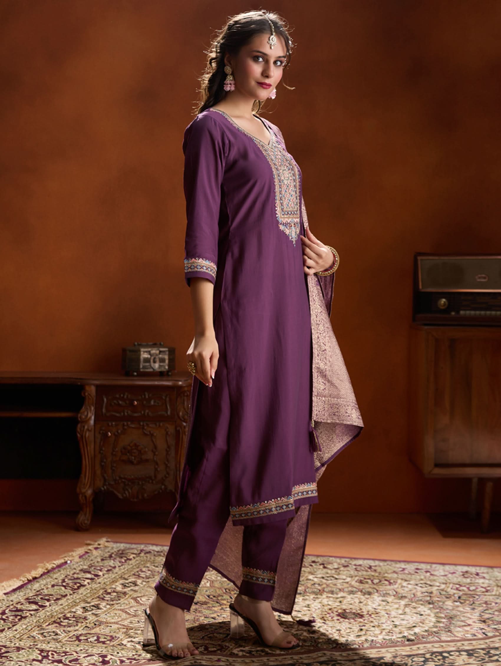 A woman wearing a purple suit set with embroidery, consisting of a kurta, pants, and a dupatta.