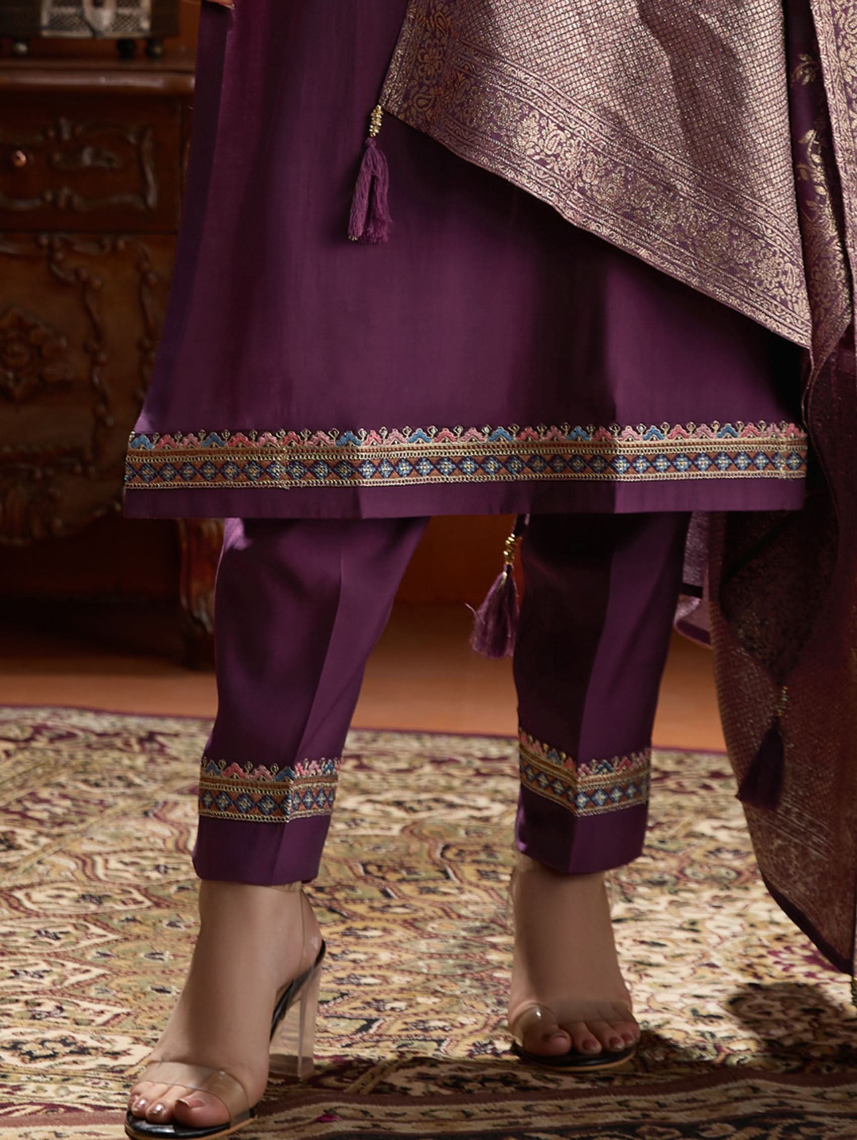 A woman wearing a purple suit set with embroidery, consisting of a kurta, pants, and a dupatta.