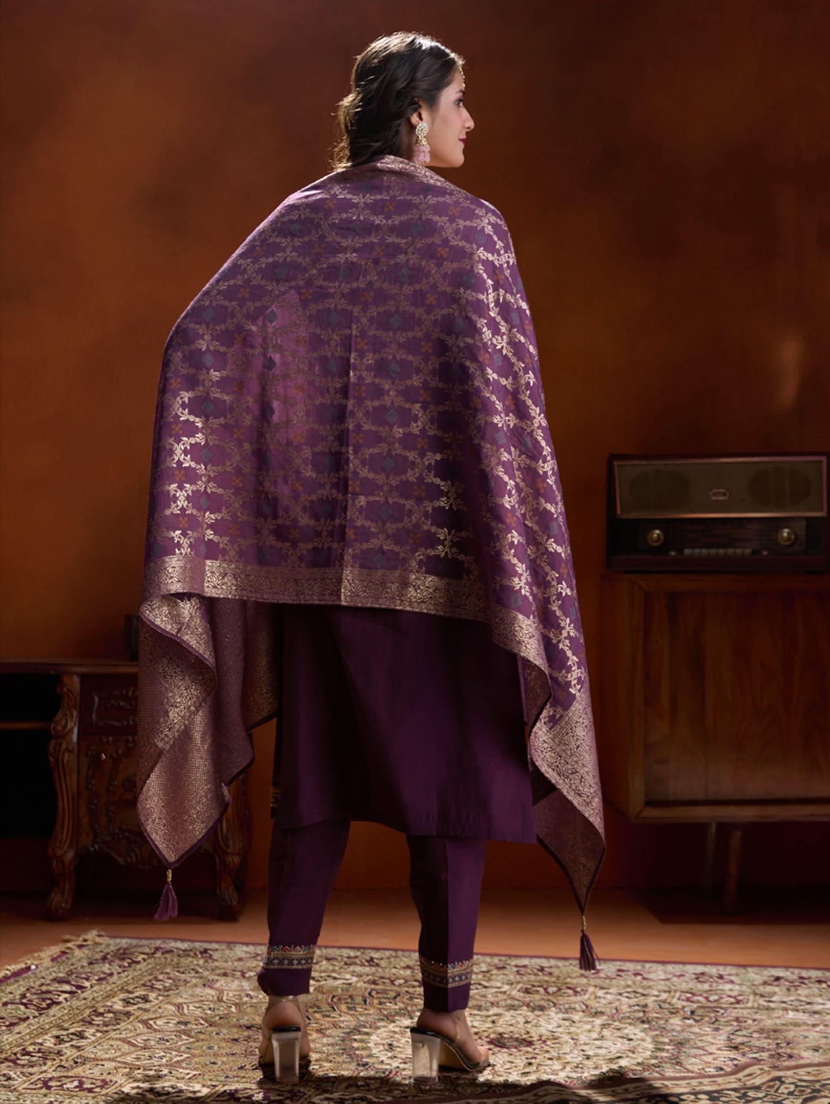 A woman wearing a purple suit set with embroidery, consisting of a kurta, pants, and a dupatta.
