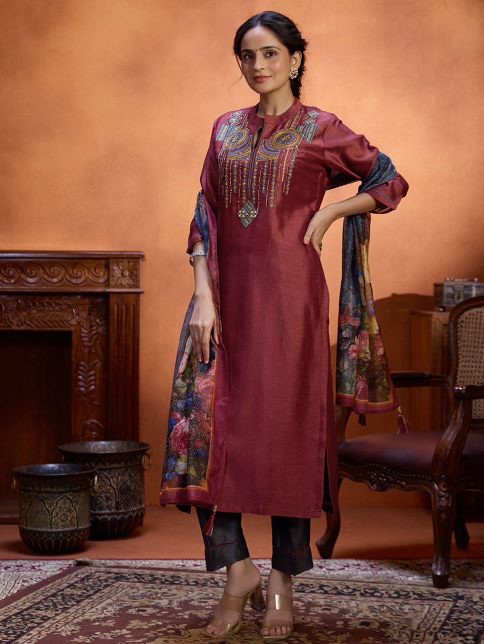 A woman wearing a maroon viscose silk suit set with computerised thread embroidery and a digitally printed dupatta.