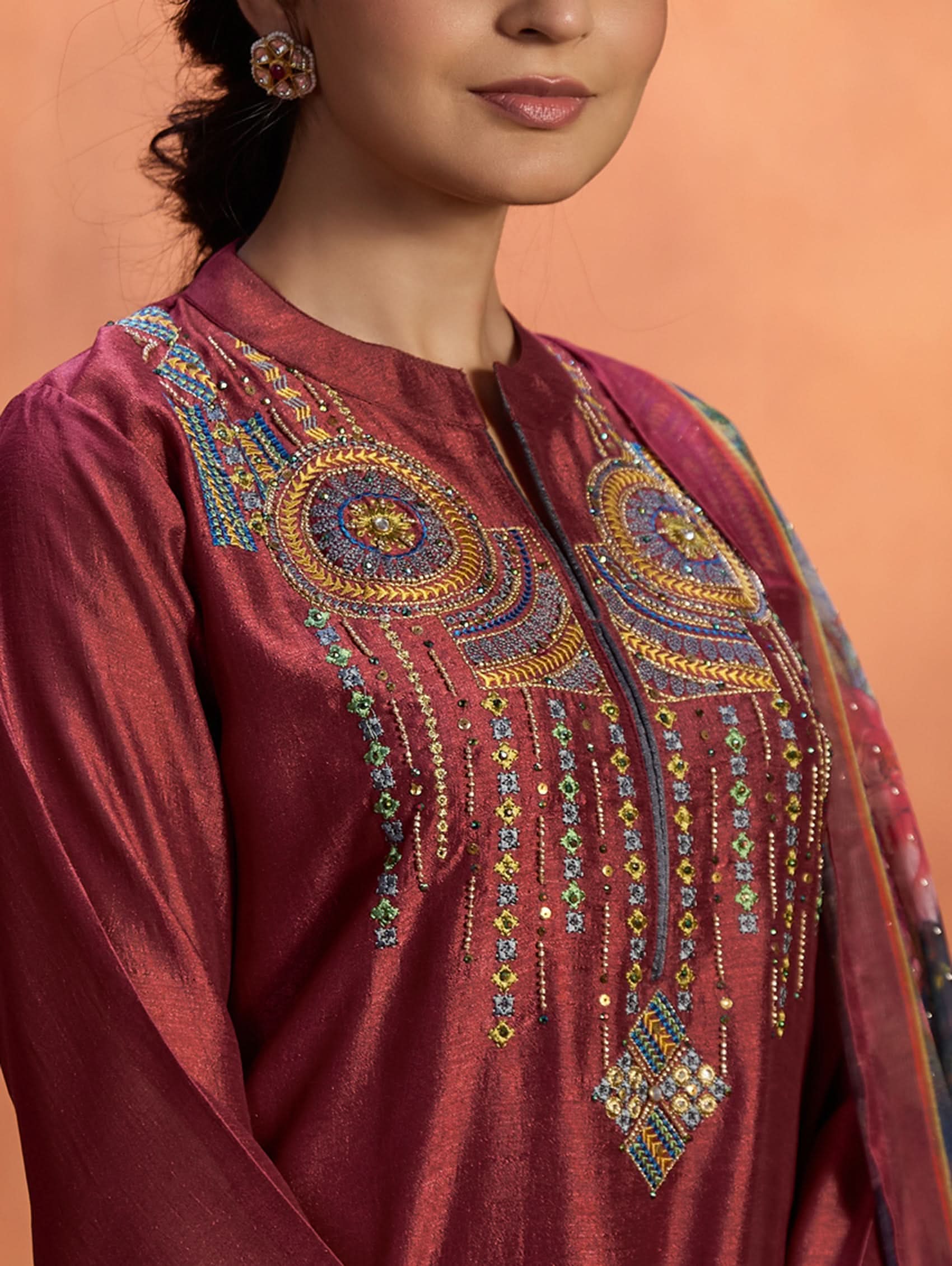 A woman wearing a maroon viscose silk suit set with computerised thread embroidery and a digitally printed dupatta.