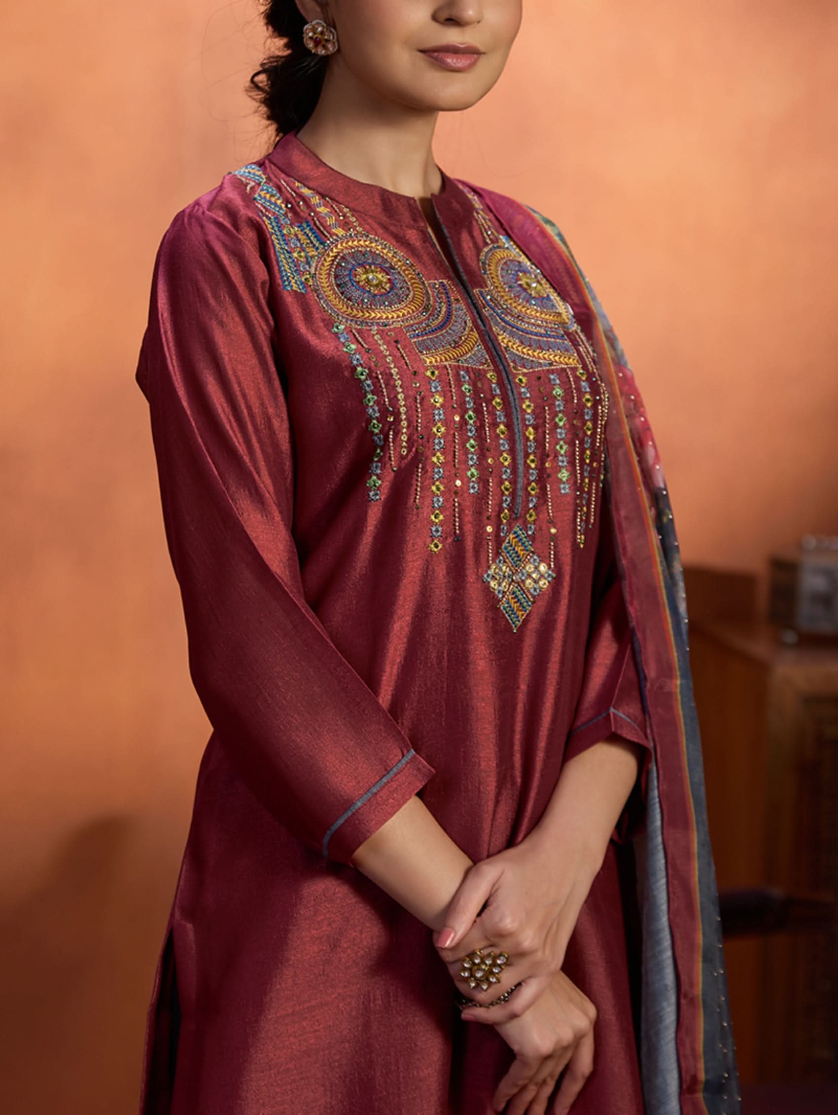 A woman wearing a maroon viscose silk suit set with computerised thread embroidery and a digitally printed dupatta.