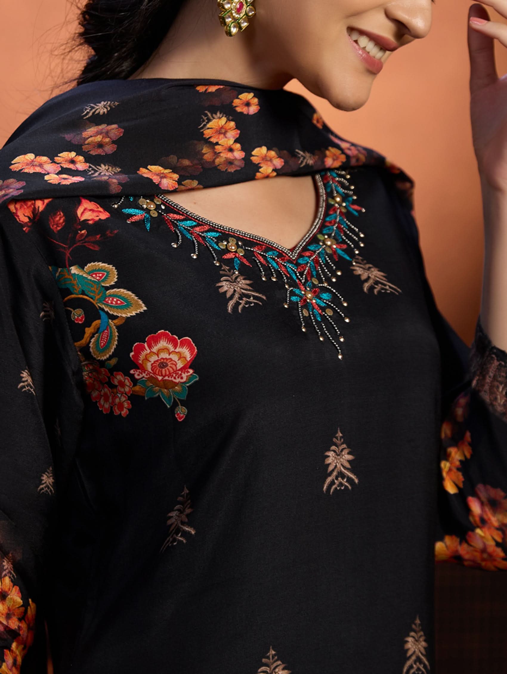 Black embroidered garment with floral patterns on a plain background