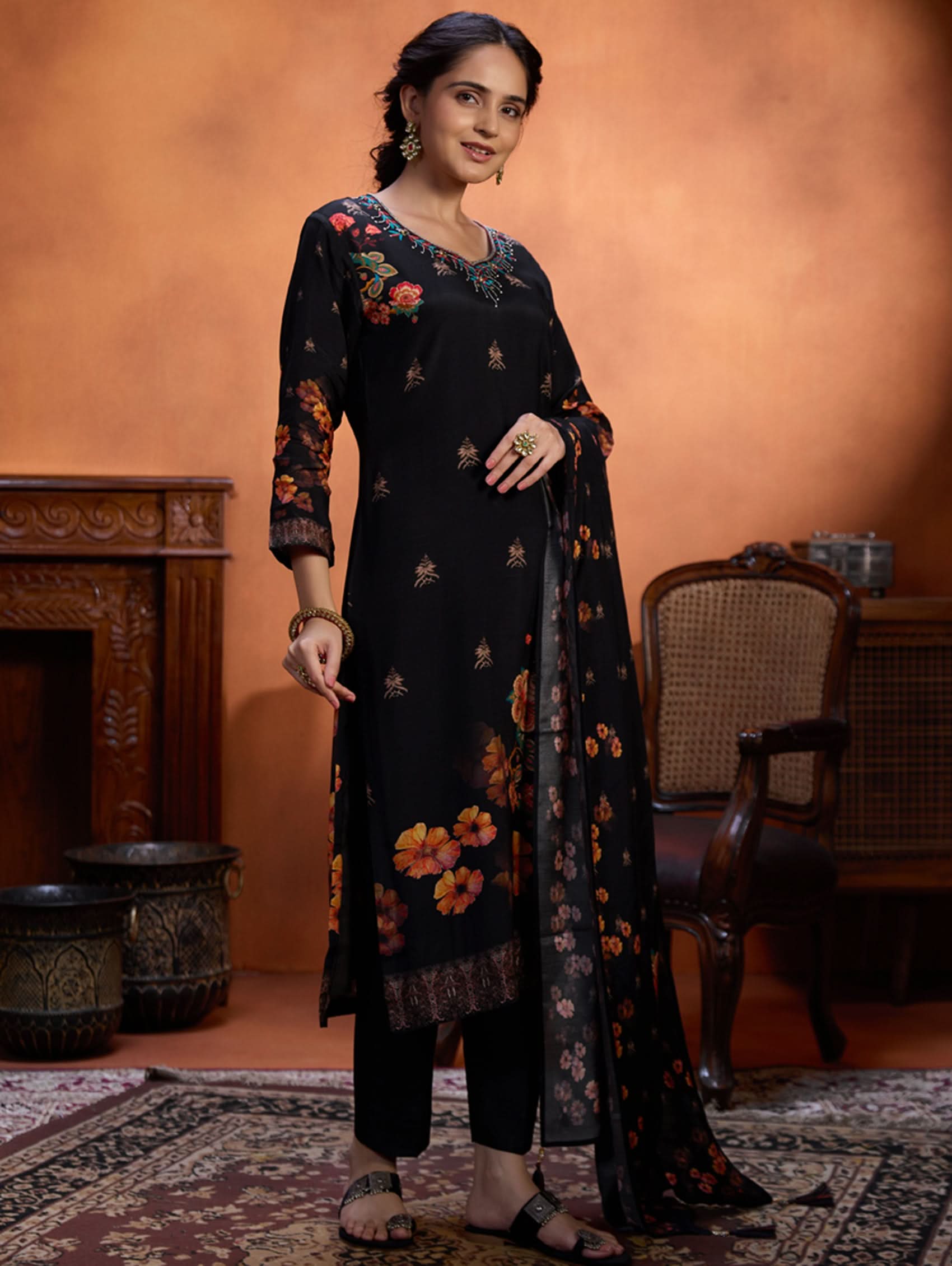 Woman wearing a black floral outfit in an indoor setting with warm lighting.