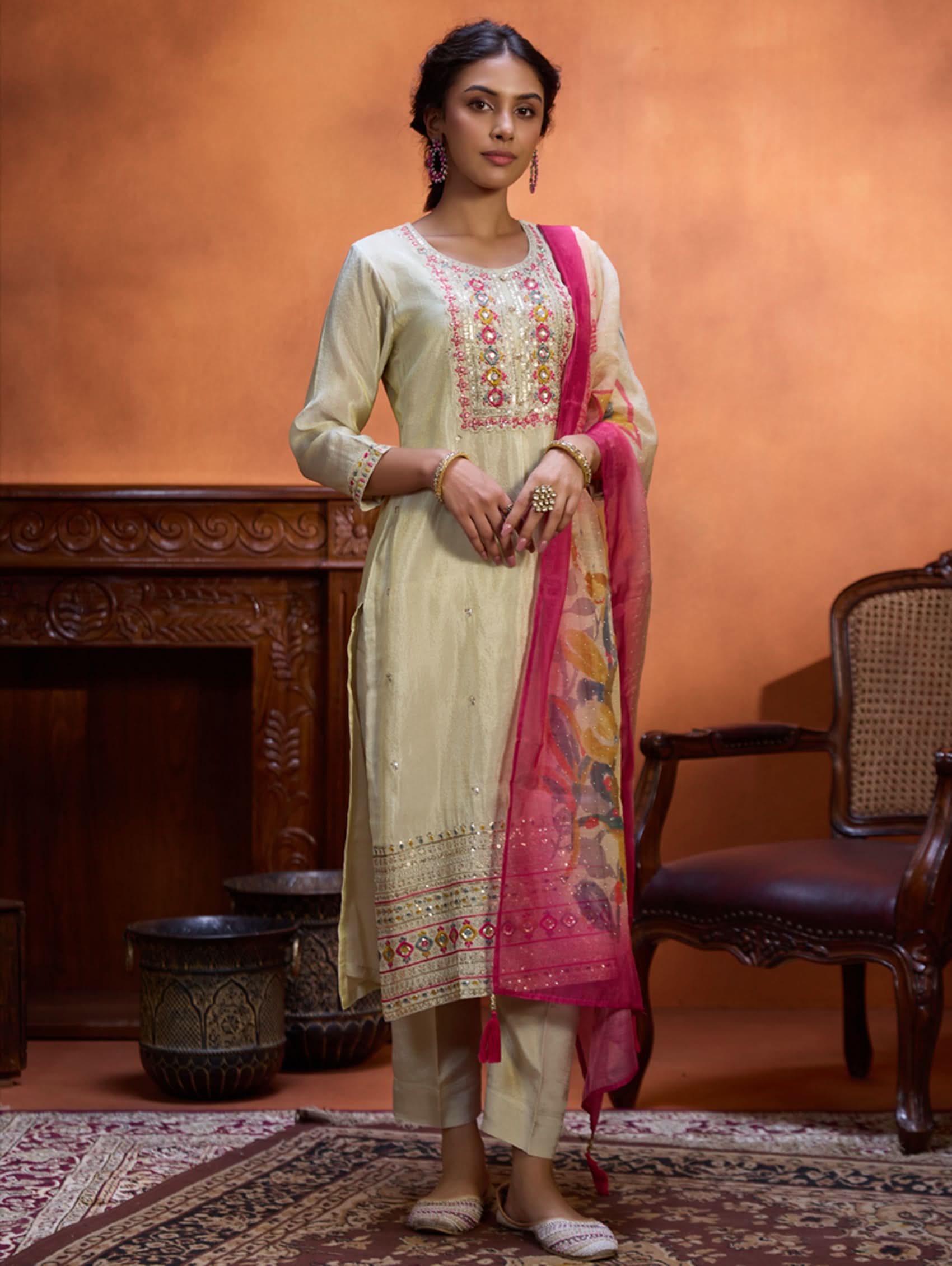 A woman wearing a traditional embroidered shimmer silk suit set with a round neckline, three-fourth sleeves, and a dupatta with digital printed chanderi silk.