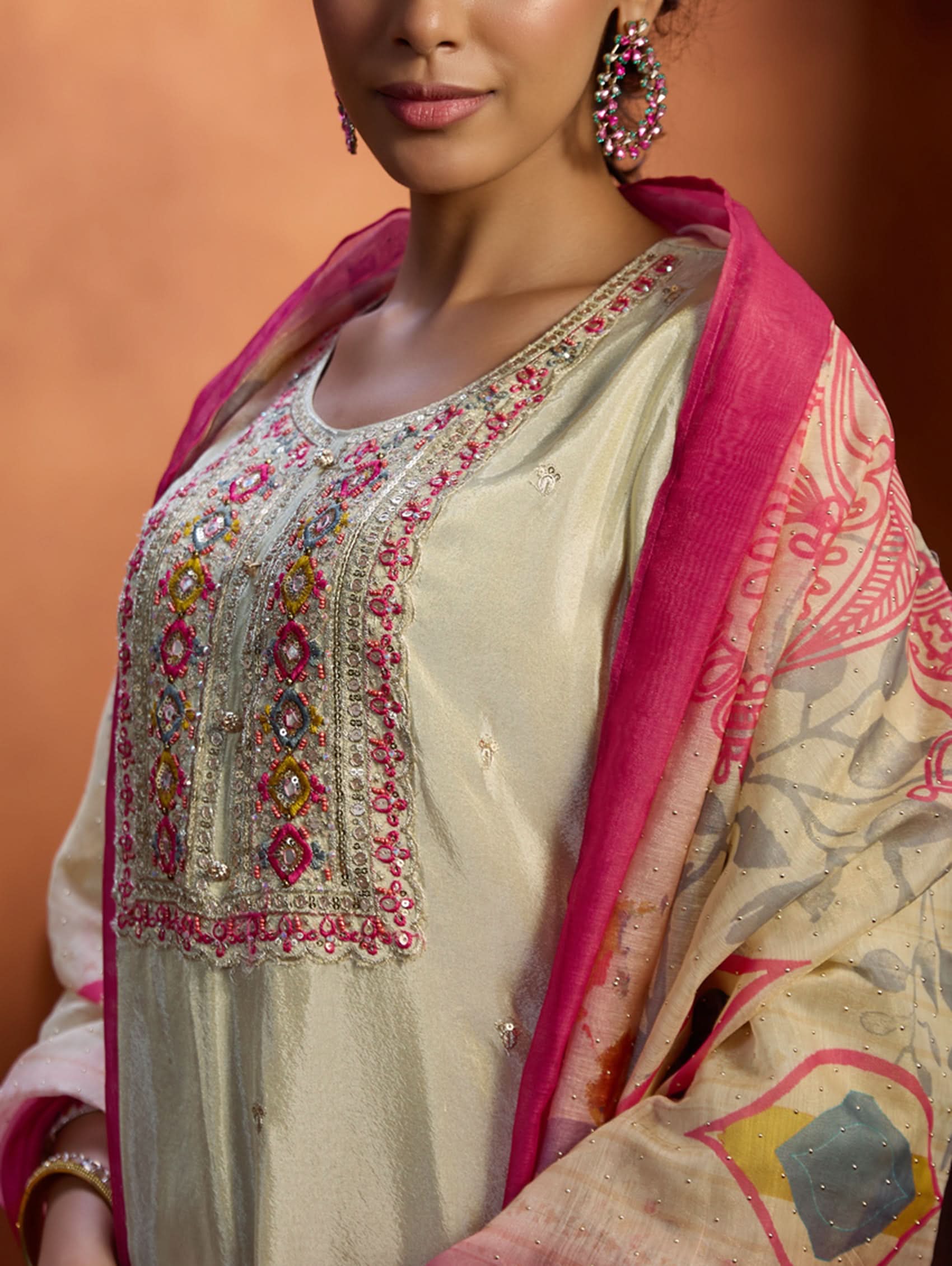 A woman wearing a traditional embroidered shimmer silk suit set with a round neckline, three-fourth sleeves, and a dupatta with digital printed chanderi silk.
