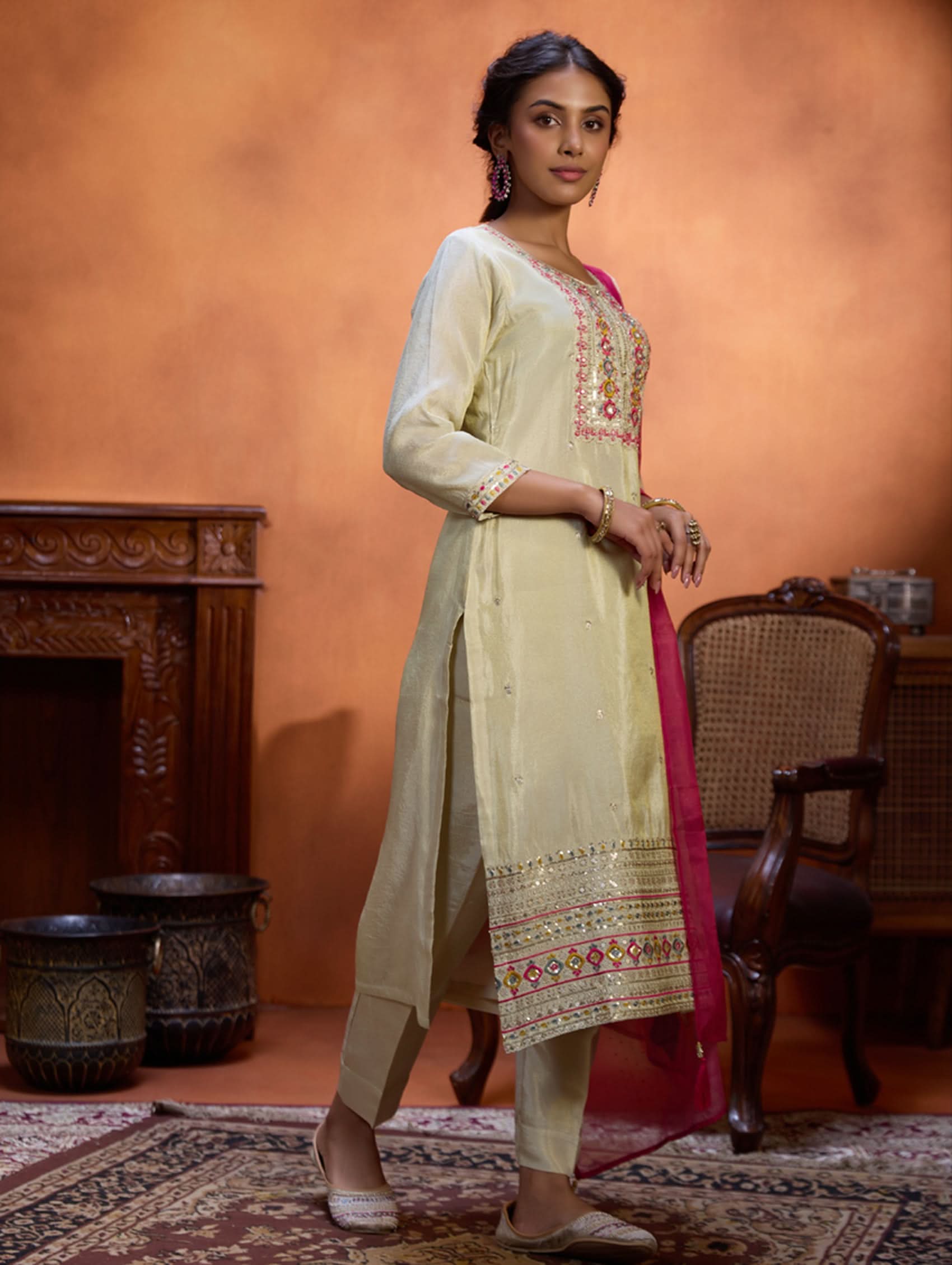 A woman wearing a traditional embroidered shimmer silk suit set with a round neckline, three-fourth sleeves, and a dupatta with digital printed chanderi silk.