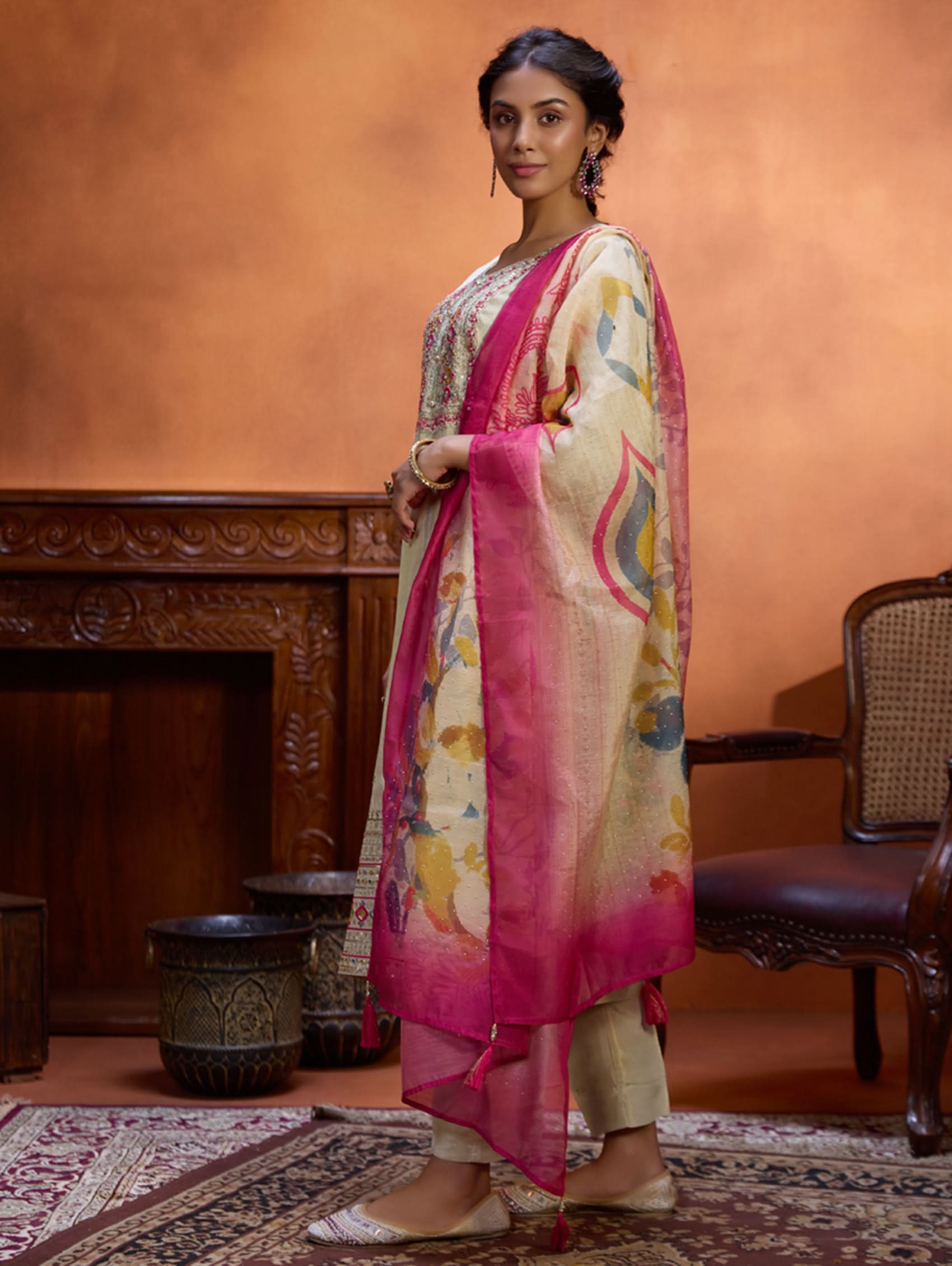 A woman wearing a traditional embroidered shimmer silk suit set with a round neckline, three-fourth sleeves, and a dupatta with digital printed chanderi silk.