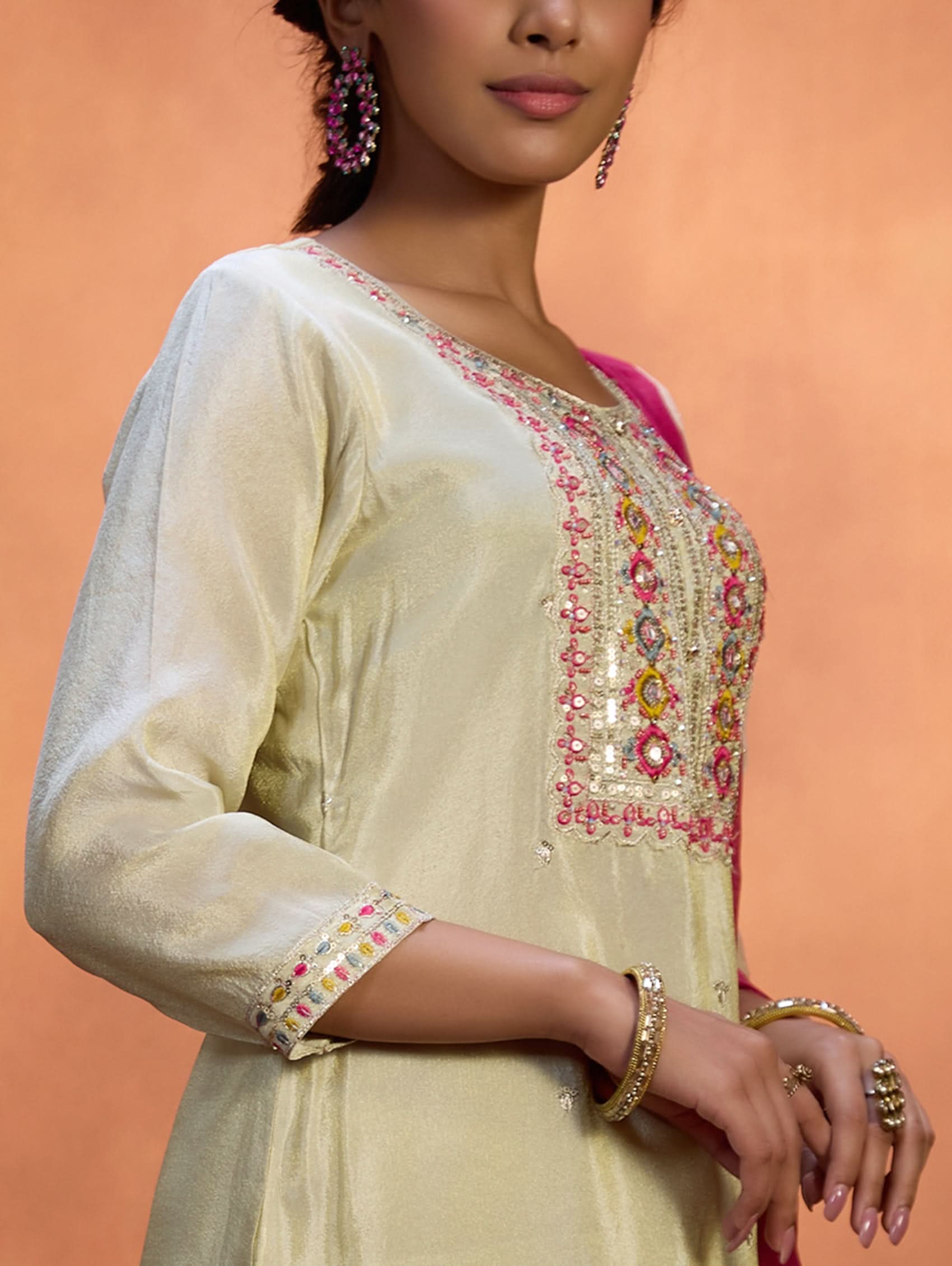 A woman wearing a traditional embroidered shimmer silk suit set with a round neckline, three-fourth sleeves, and a dupatta with digital printed chanderi silk.